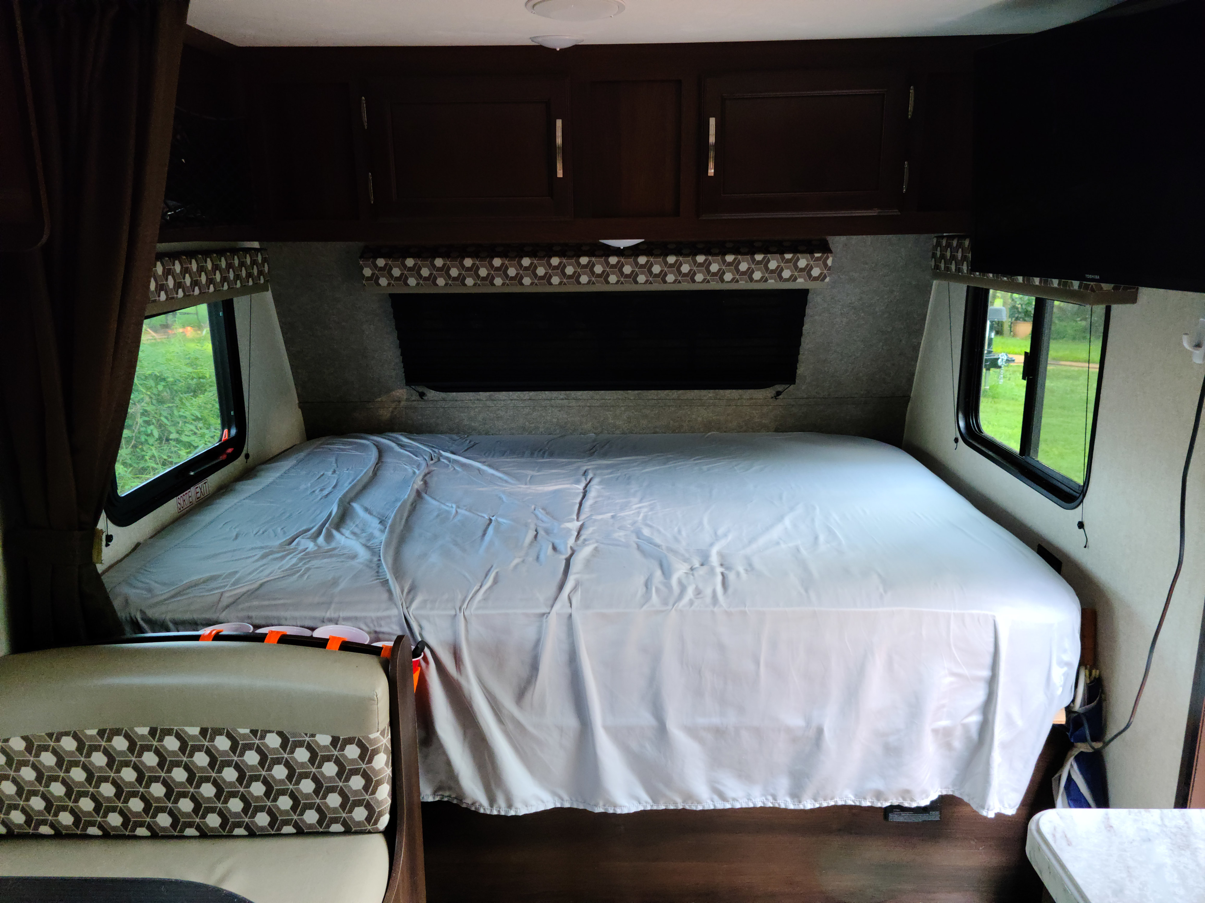 Inside an RV rental: a cozy bedroom with a bed, storage cabinets, and scenic window views.. Jayco Jay Flight SLX Baja Edition 2020
