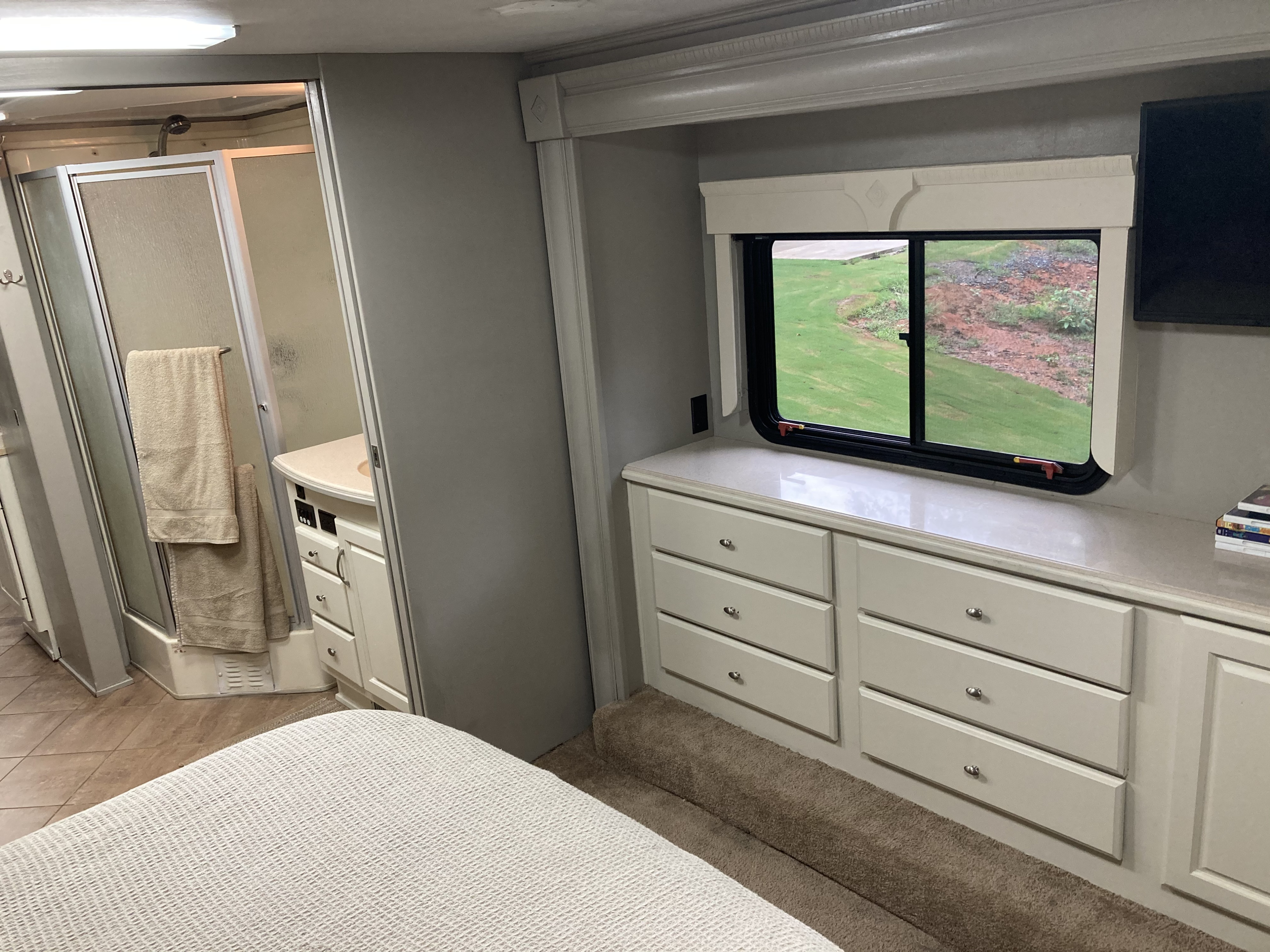 Inside a comfortable RV rental: Bedroom with storage, a scenic window view, and a separate, fully equipped bathroom.. Monaco Windsor 2004