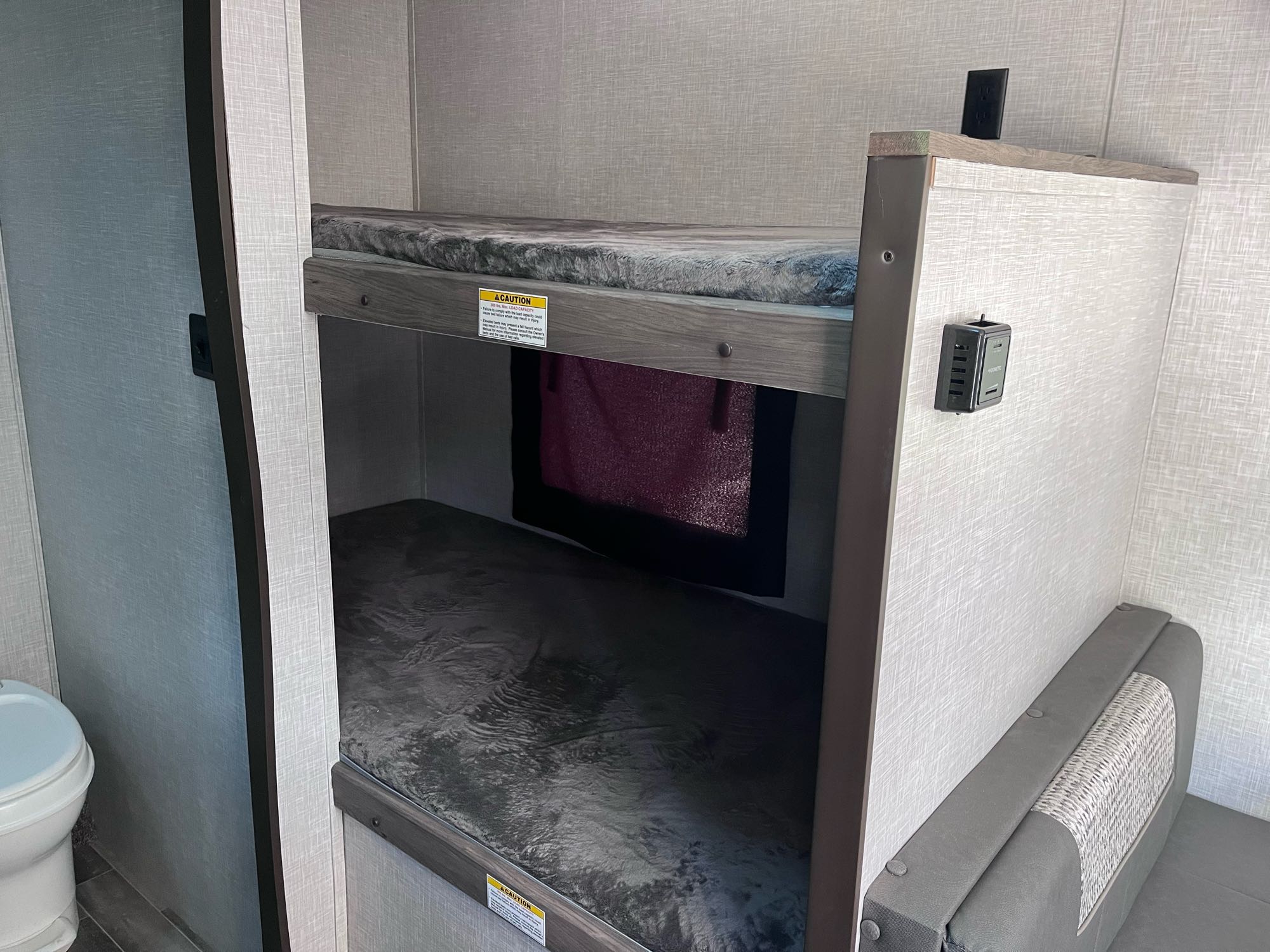 RV rental interior: Bunk beds, toilet on left, dinette seat on right. Compact and functional living area.. Crossroads RV Zinger Lite 2021