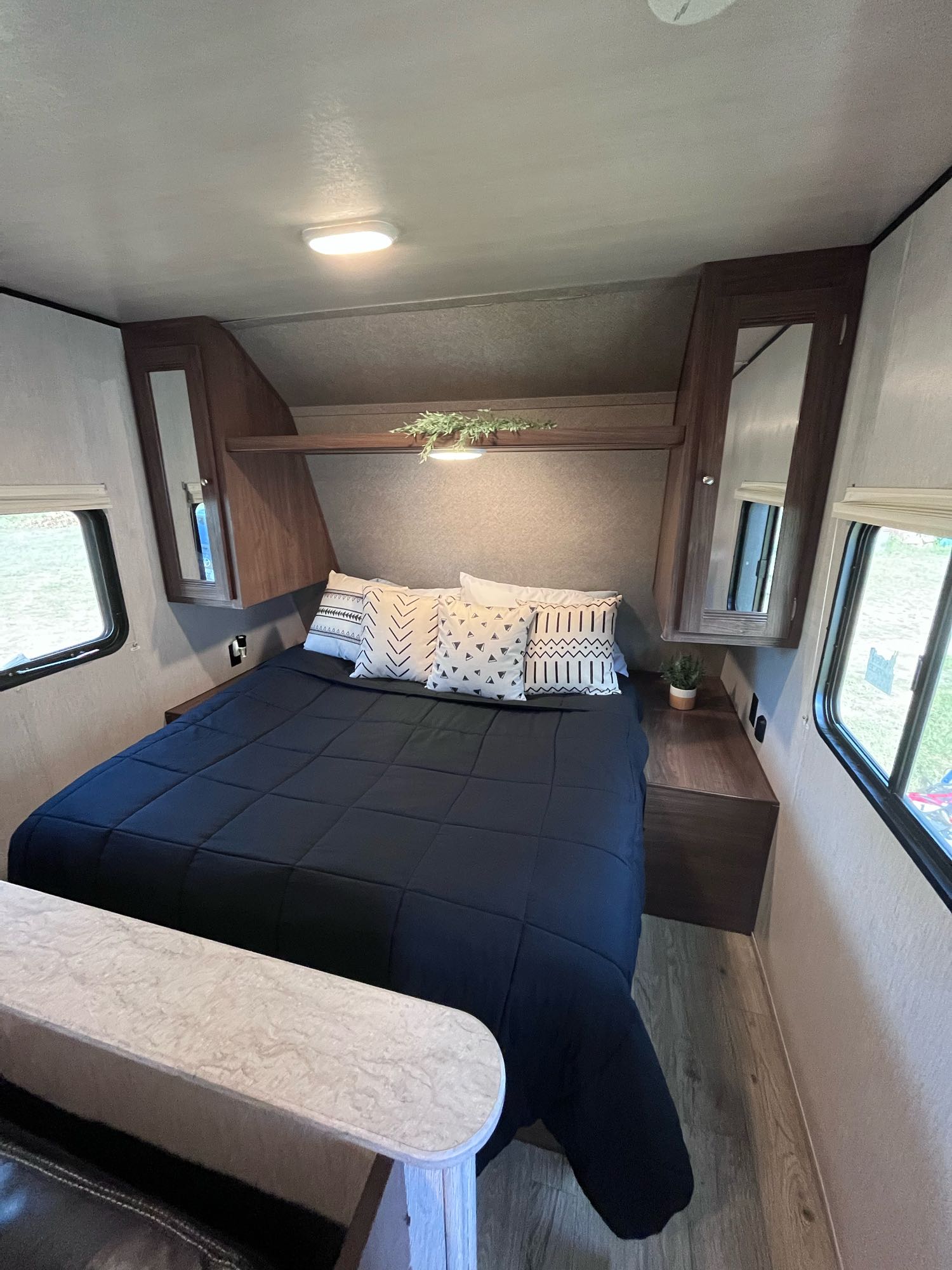 Relax in this modern RV rental bedroom, featuring a comfy bed, dark wood cabinets, and bright windows.. Heartland RVs Prowler Lynx 2018
