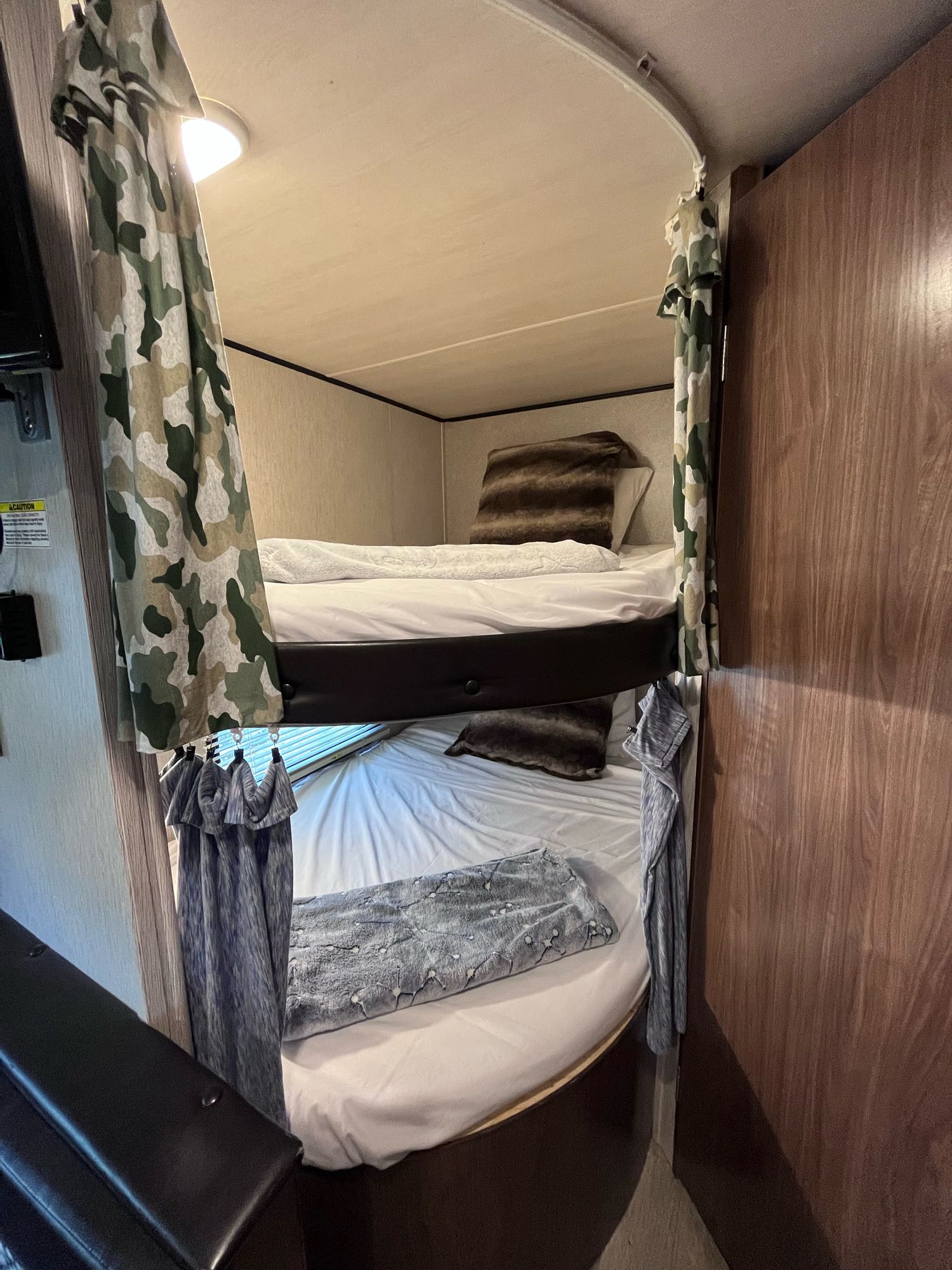 An RV rental interior with two bunk beds, complete with white bedding and camouflage privacy curtains for a comfortable stay.. Heartland RVs Prowler Lynx 2018