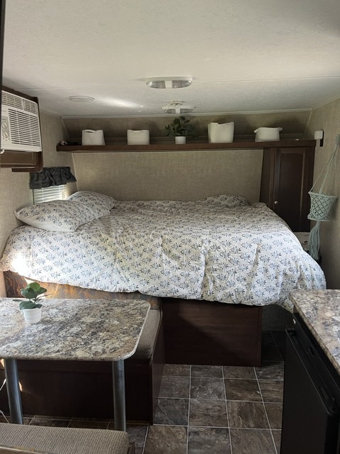This RV rental interior features a cozy bed, a compact dinette, and a small kitchen area, perfect for travel.. Keystone RV Hideout 175LHS 2015