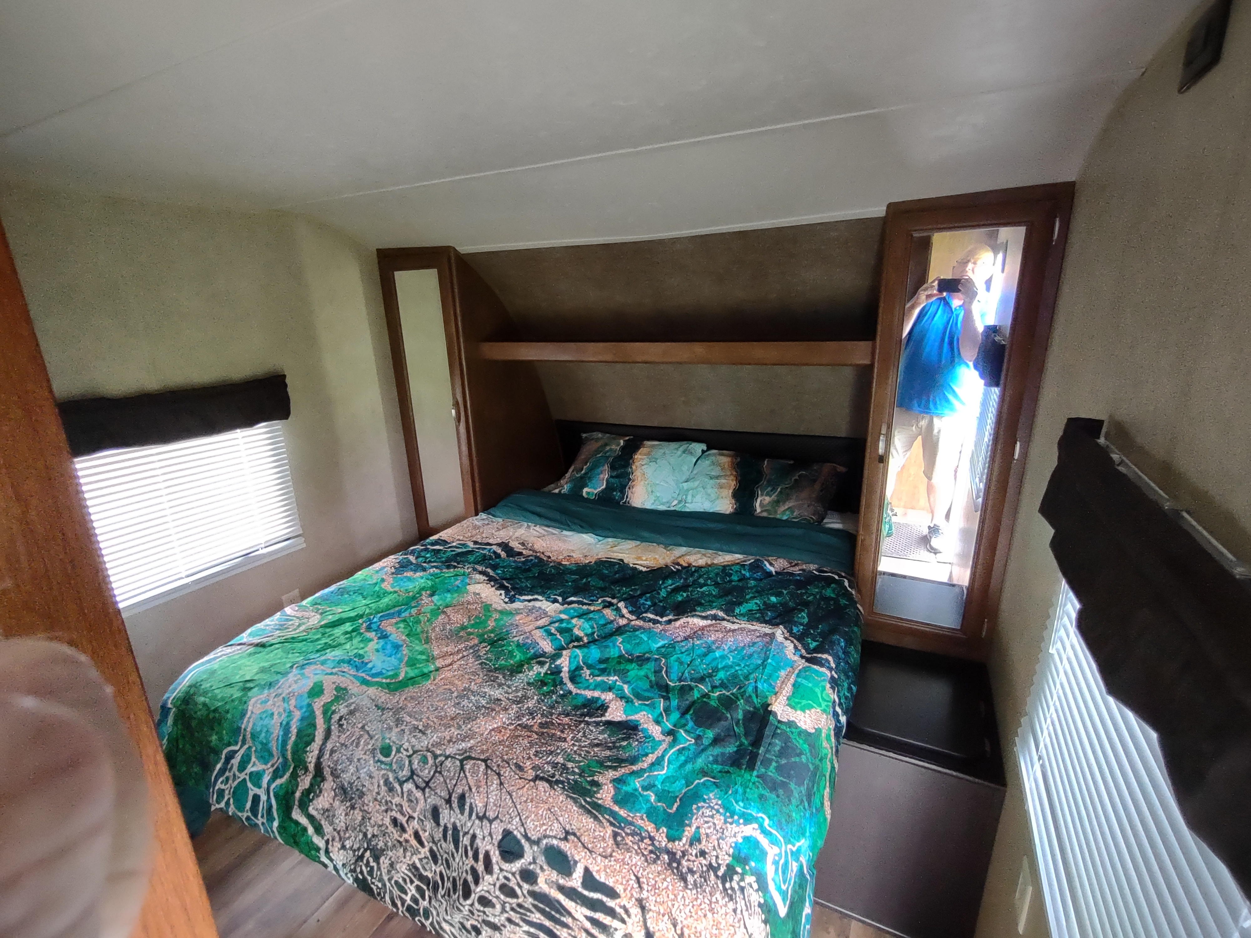 Spacious RV rental bedroom featuring colorful bedding, overhead storage, and a mirror reflection. Perfect for your travels!. Forest River Salem 2017