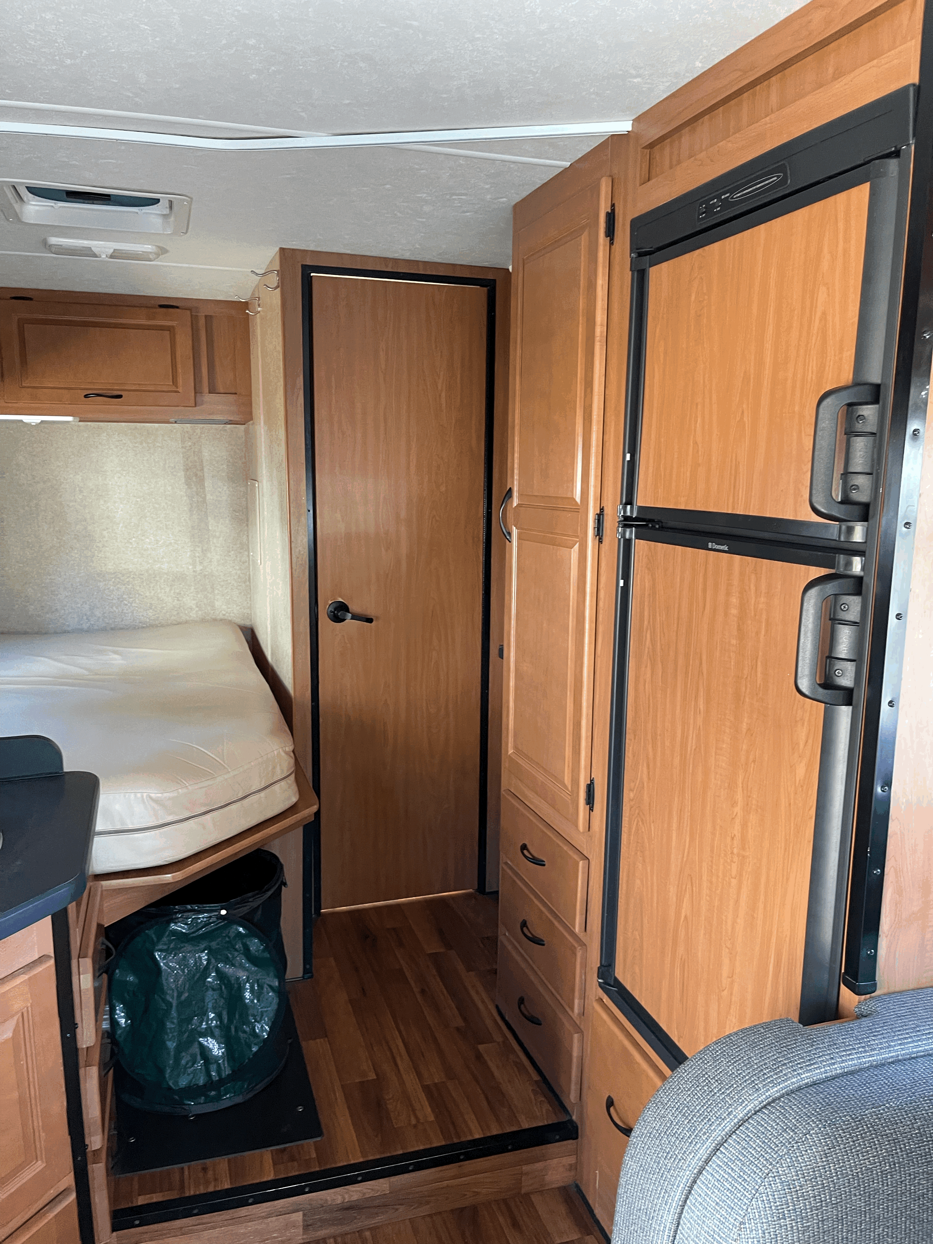 An RV rental's efficient interior, showing a bed, built-in fridge, and wooden cabinets for convenient travel.. Thor Majestic 2017