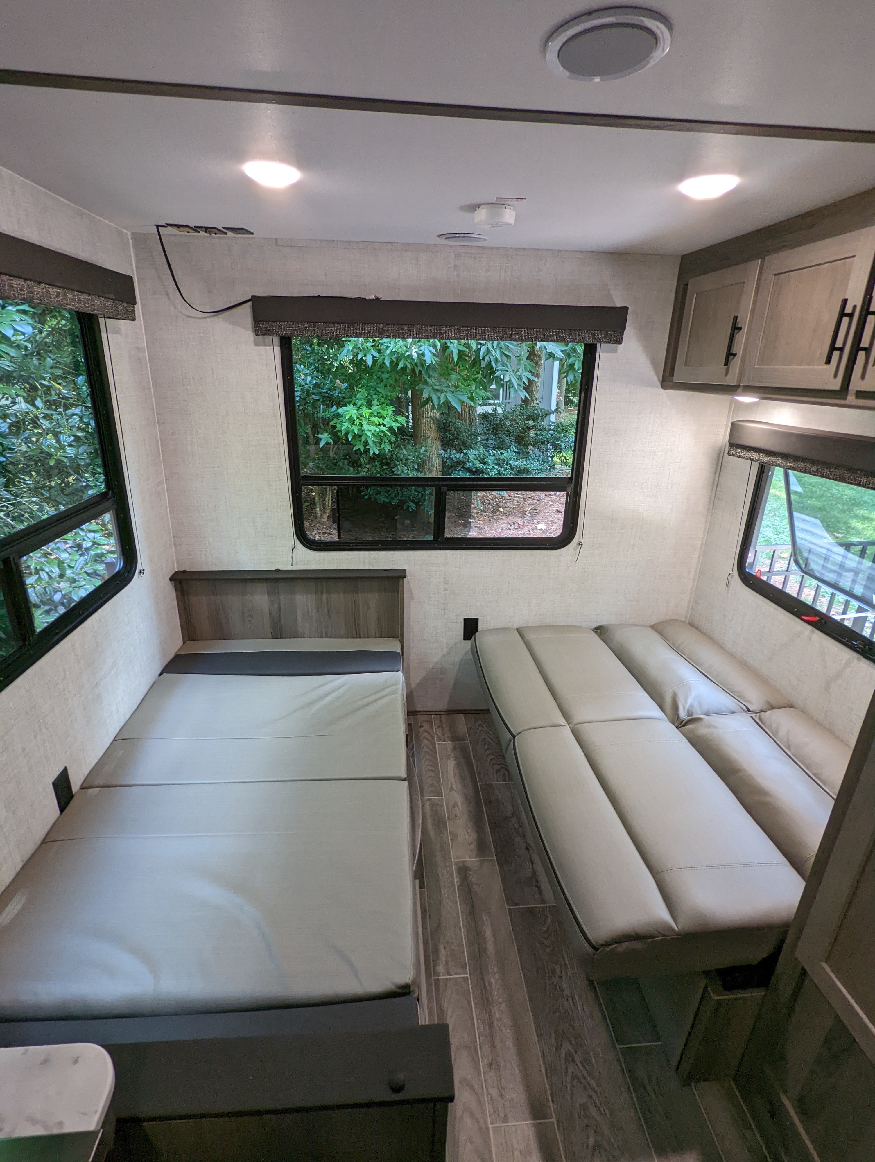 Cozy RV rental interior featuring a convertible sofa and a bed, perfect for compact travel living with bright windows.. Gulf Stream Kingsport 2022