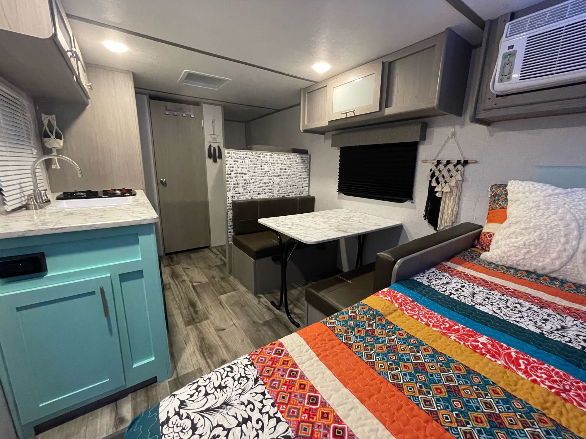 Explore this RV rental's interior: a kitchen with teal cabinets, dining booth, comfy bed, and AC unit.. Dutchmen Coleman Lantern LT 2022