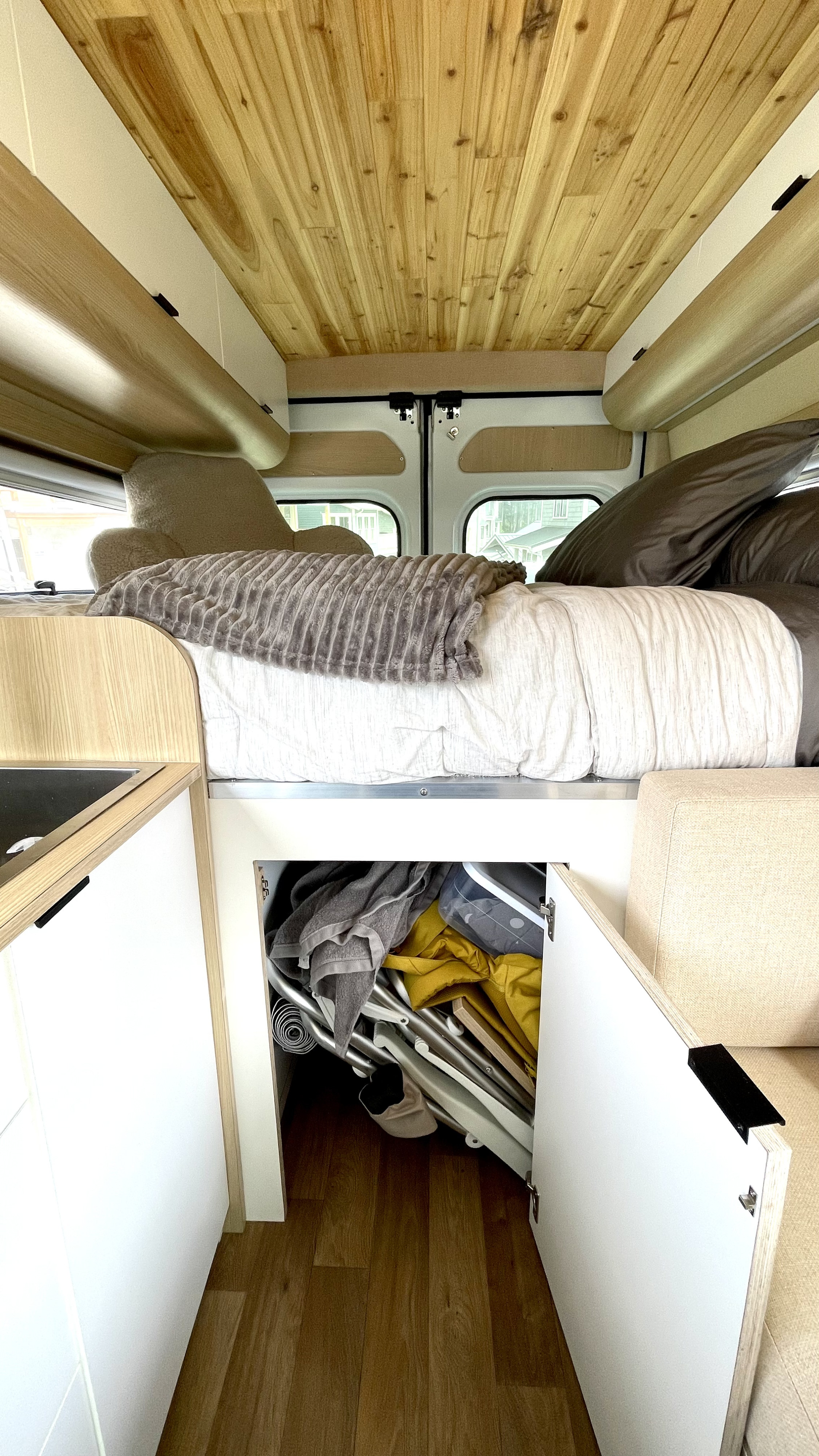 Spacious RV rental interior featuring a comfy bed, wood-paneled ceiling, and smart under-bed storage for your gear.. Dodge Ram Promaster 2500 2022