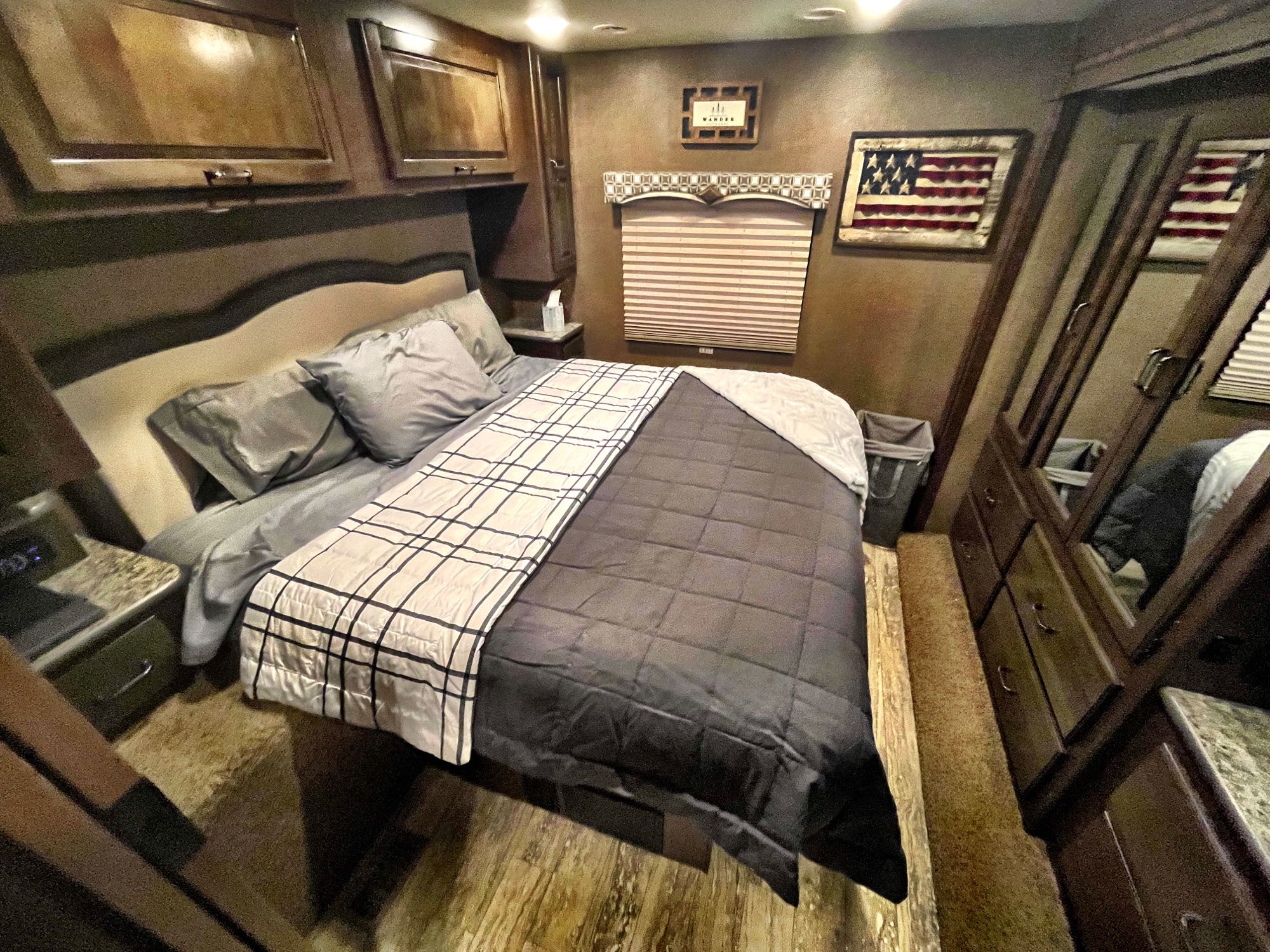 Cozy RV rental bedroom showing a bed with gray bedding, overhead storage, and mirrored wardrobe doors.. Thor Hurricane 2017