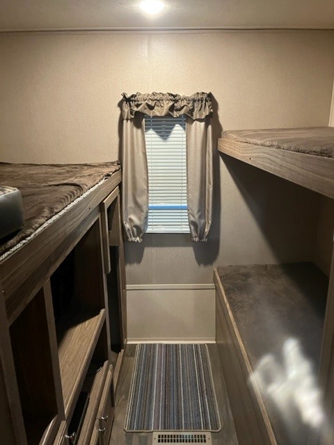 Compact RV rental interior featuring bunk beds, a window, and a striped rug. A cozy sleeping area for your next adventure.. Forest River Shasta Revere 2018