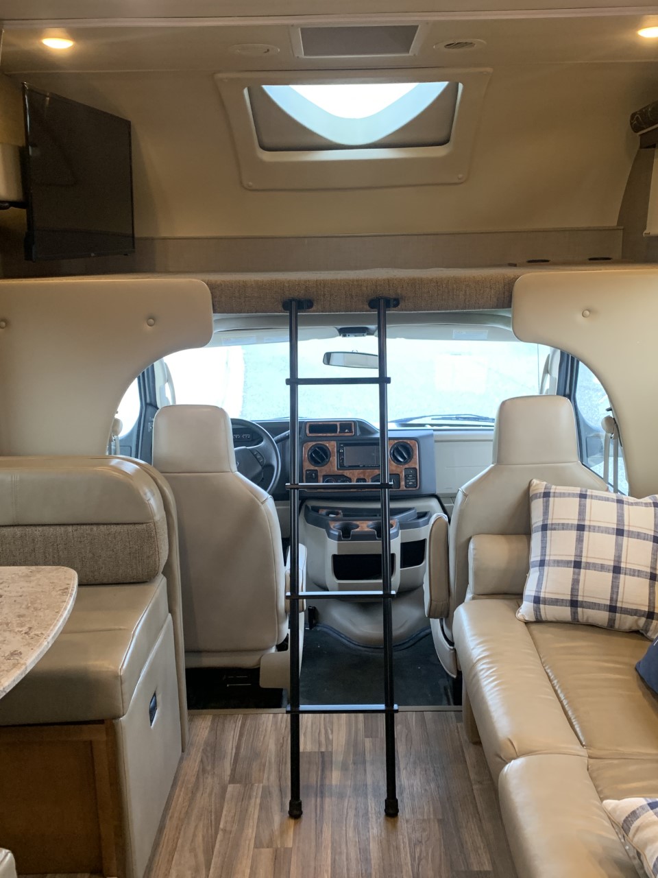 Step into this bright RV rental interior featuring a dinette, sofa, bunk with ladder, TV, and front cockpit.. Thor Quantum 2017