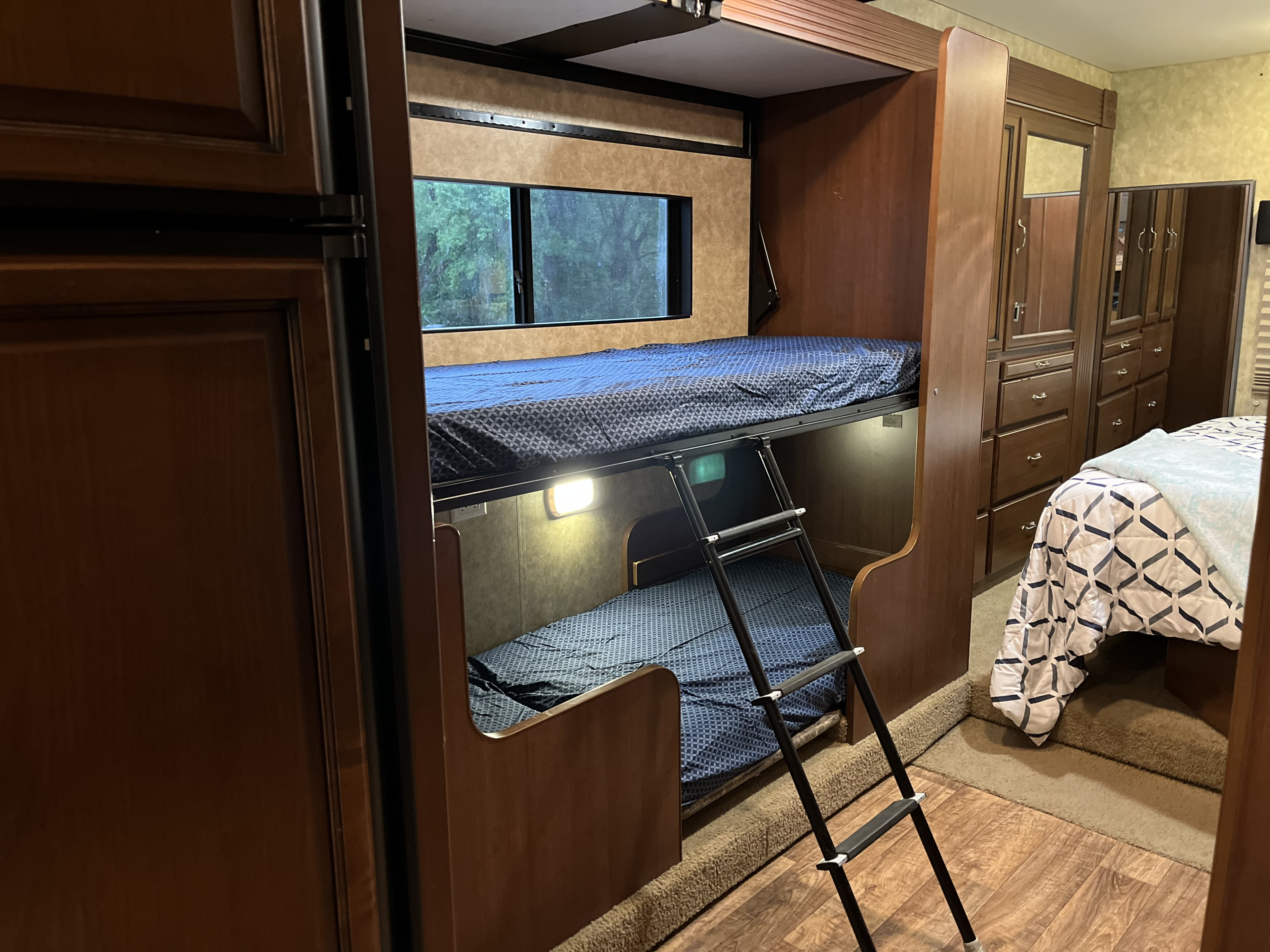 RV rental interior featuring comfortable bunk beds, a ladder, and a master bedroom area, ideal for family travel.. Fleetwood Storm 32BH 2013