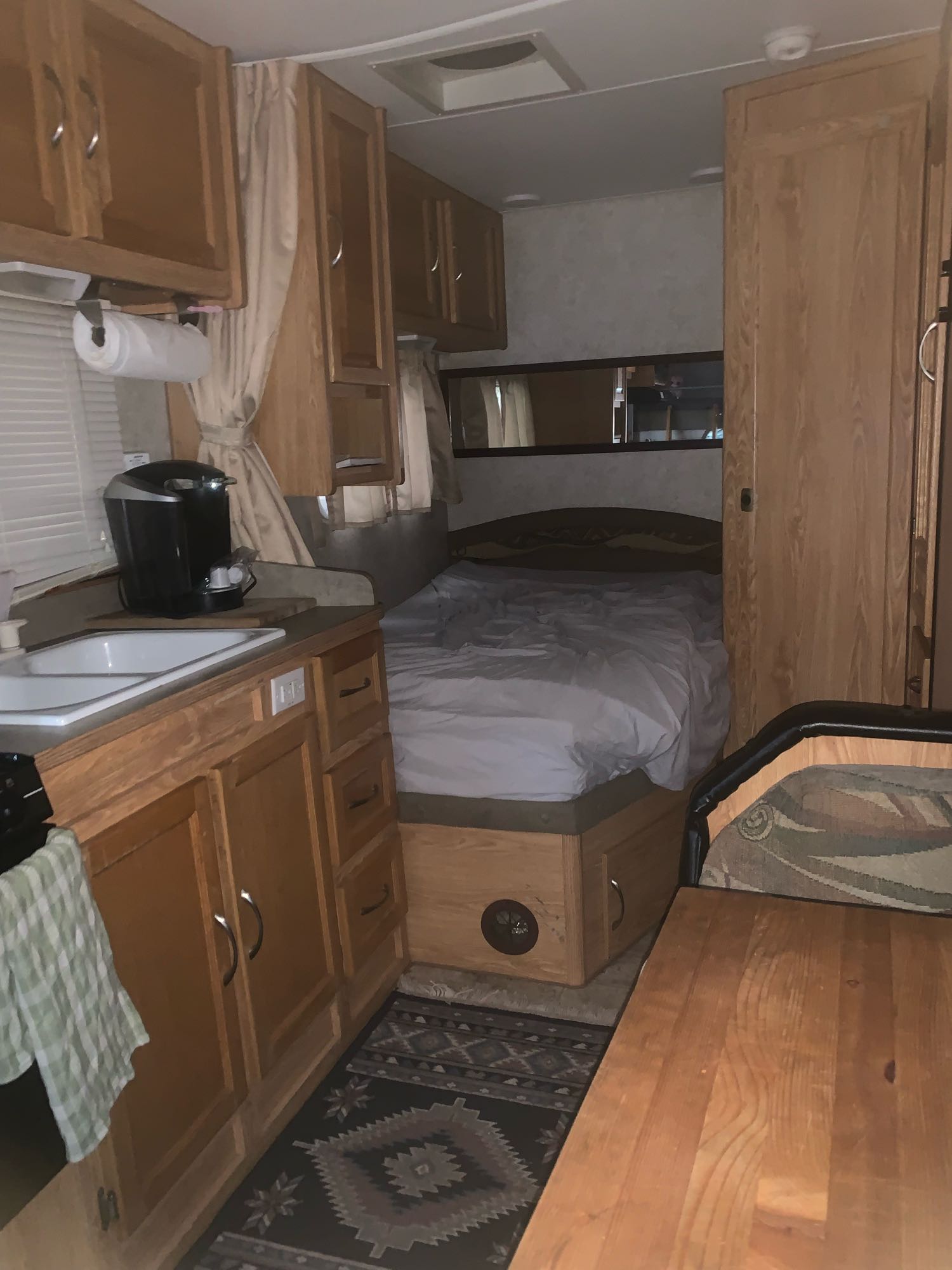 Step inside this inviting rv rental, showcasing its compact kitchen with sink, comfy bed, and dining space. Warm wood accents throughout.. Adventurer Adventurer Motorhome 2006