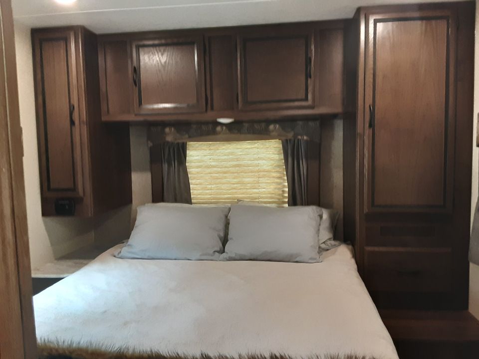 Cozy RV rental bedroom featuring a comfortable bed, ample overhead, and side cabinets. Ideal for travel comfort.. Forest River Coachmen Freelander 2018