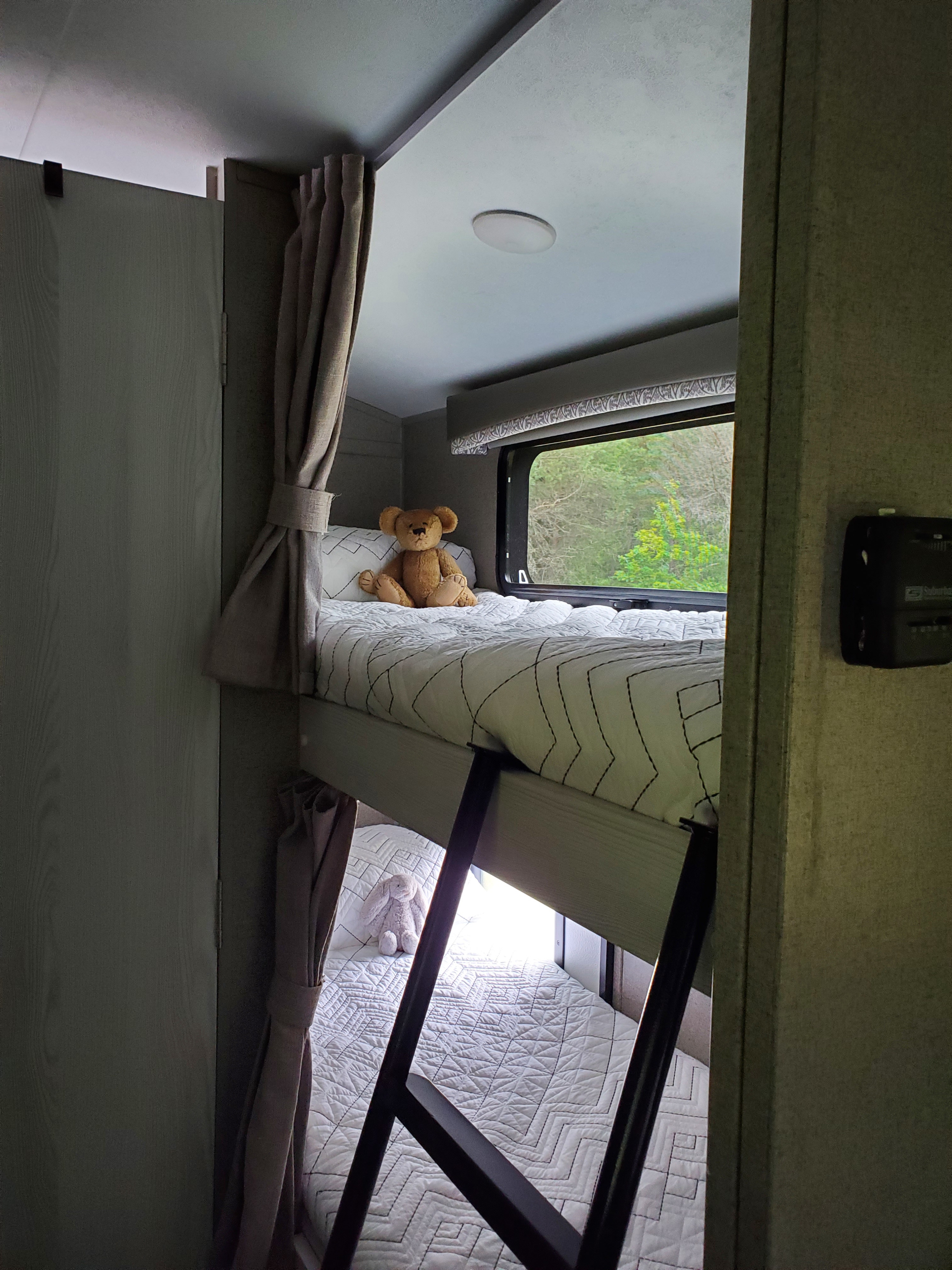 Cozy RV rental interior showing bunk beds with a teddy bear on top and a plush rabbit below, visible through a ladder.. Forest River Rockwood Geo Pro 2019