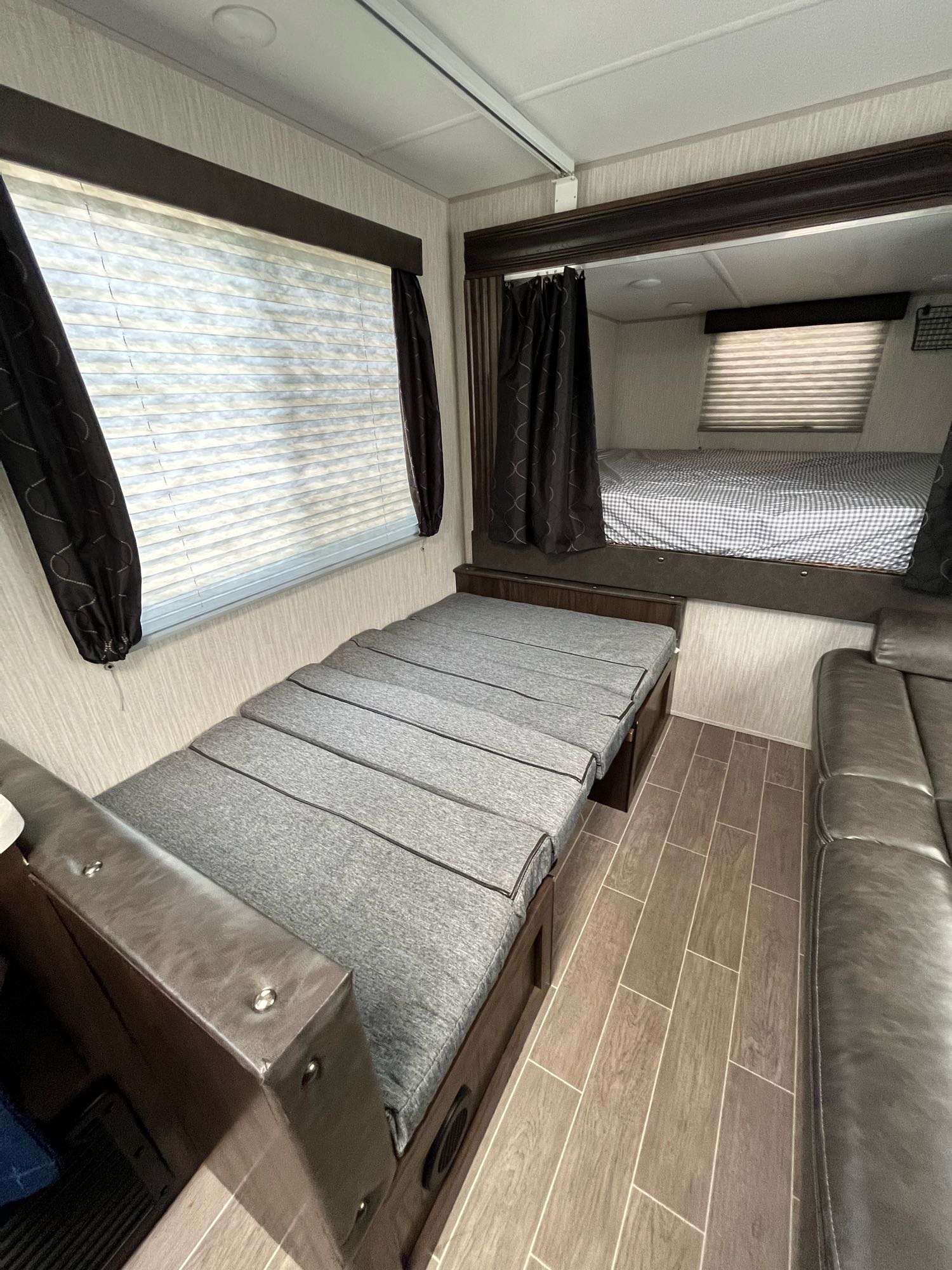 RV rental interior featuring a lower convertible bed/sofa, an upper bunk, and a comfy sofa, ideal for sleeping and lounging.. Forest River Cherokee Grey Wolf 2020