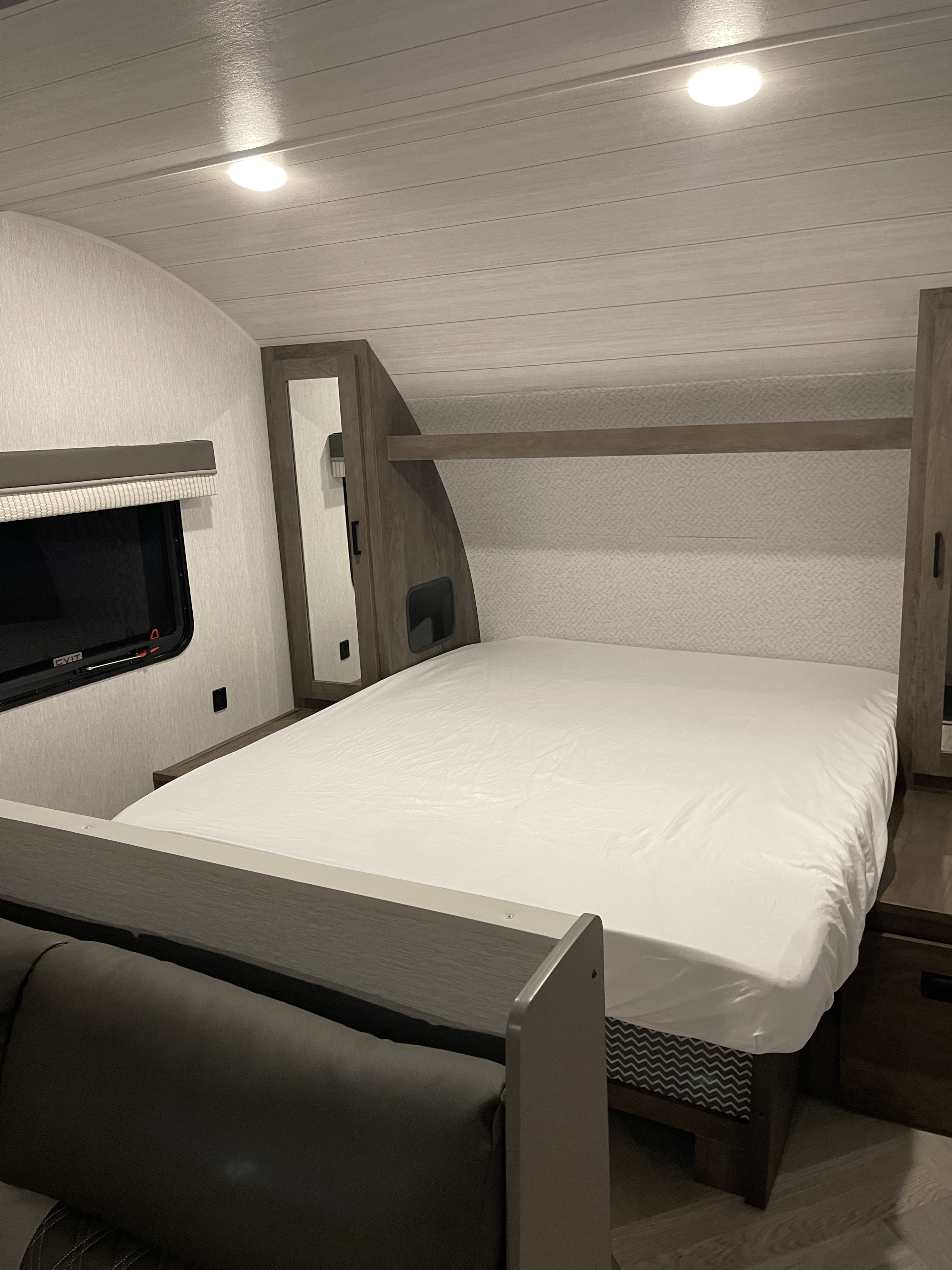 RV rental: View of a compact, well-lit RV bedroom featuring a bed with white sheets, built-in cabinets, and a side window.. Forest River Salem Cruise Lite 2022