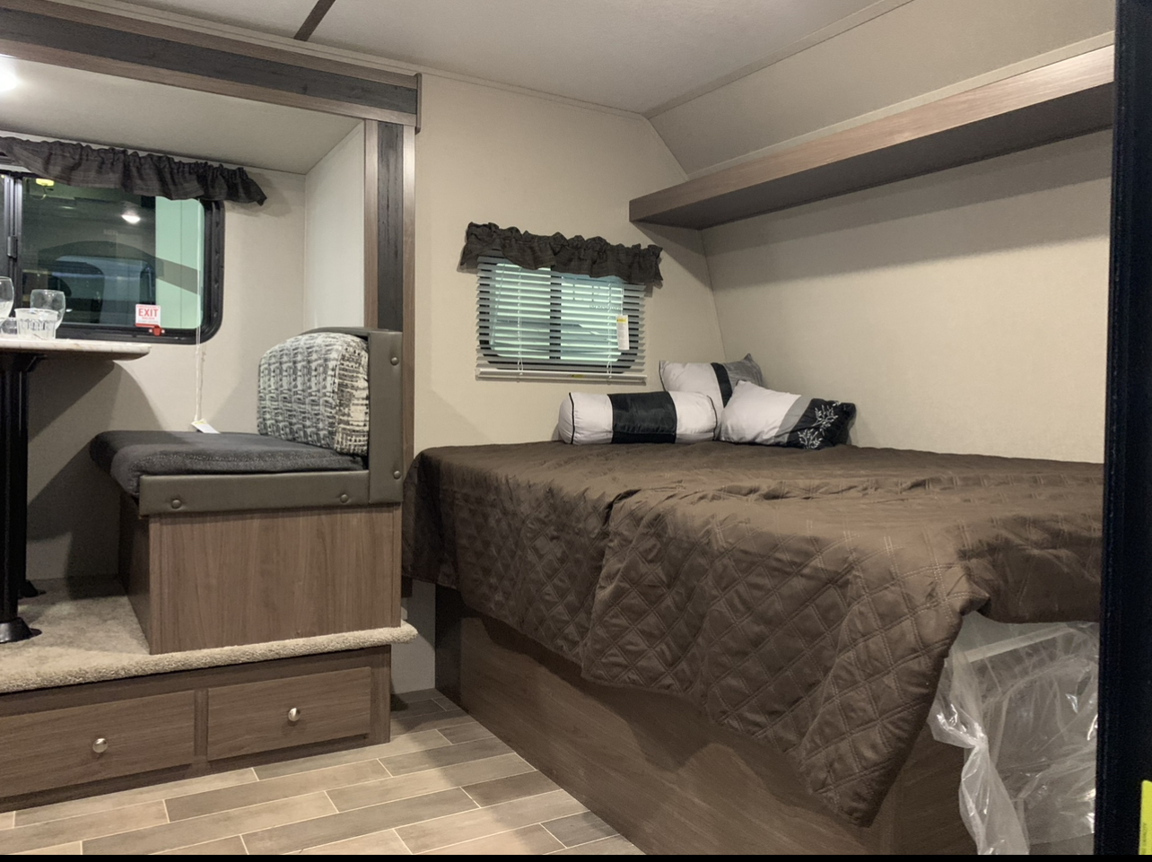 Cozy RV rental interior featuring a quilted brown bed, dinette with patterned cushions, and under-bed storage. Ideal for road trips.. Keystone RV Hideout 2019
