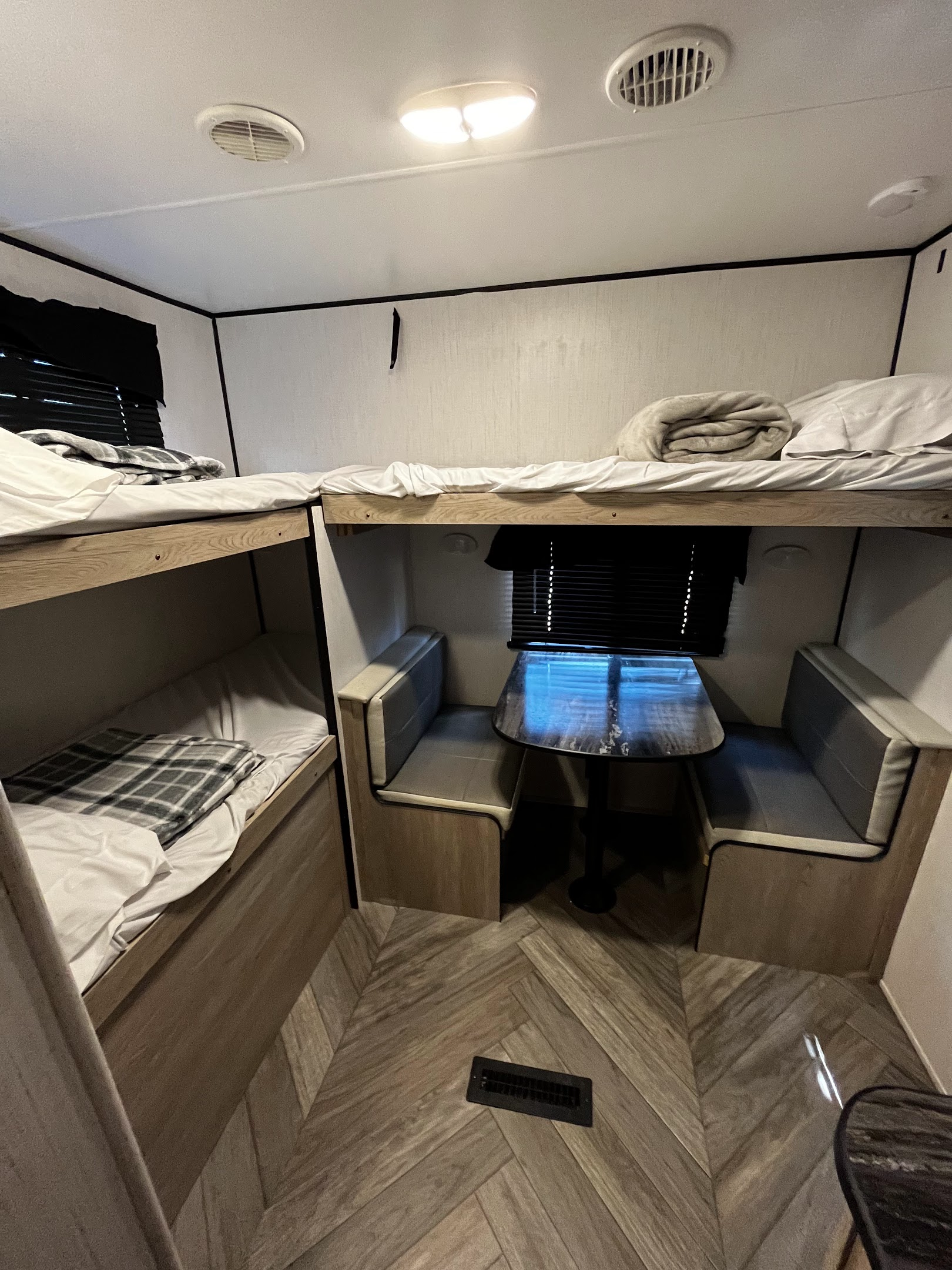 RV rental interior: cozy bunk beds, a dinette with table and bench seating, and wood-pattern flooring.. Heartland Prowler 2022