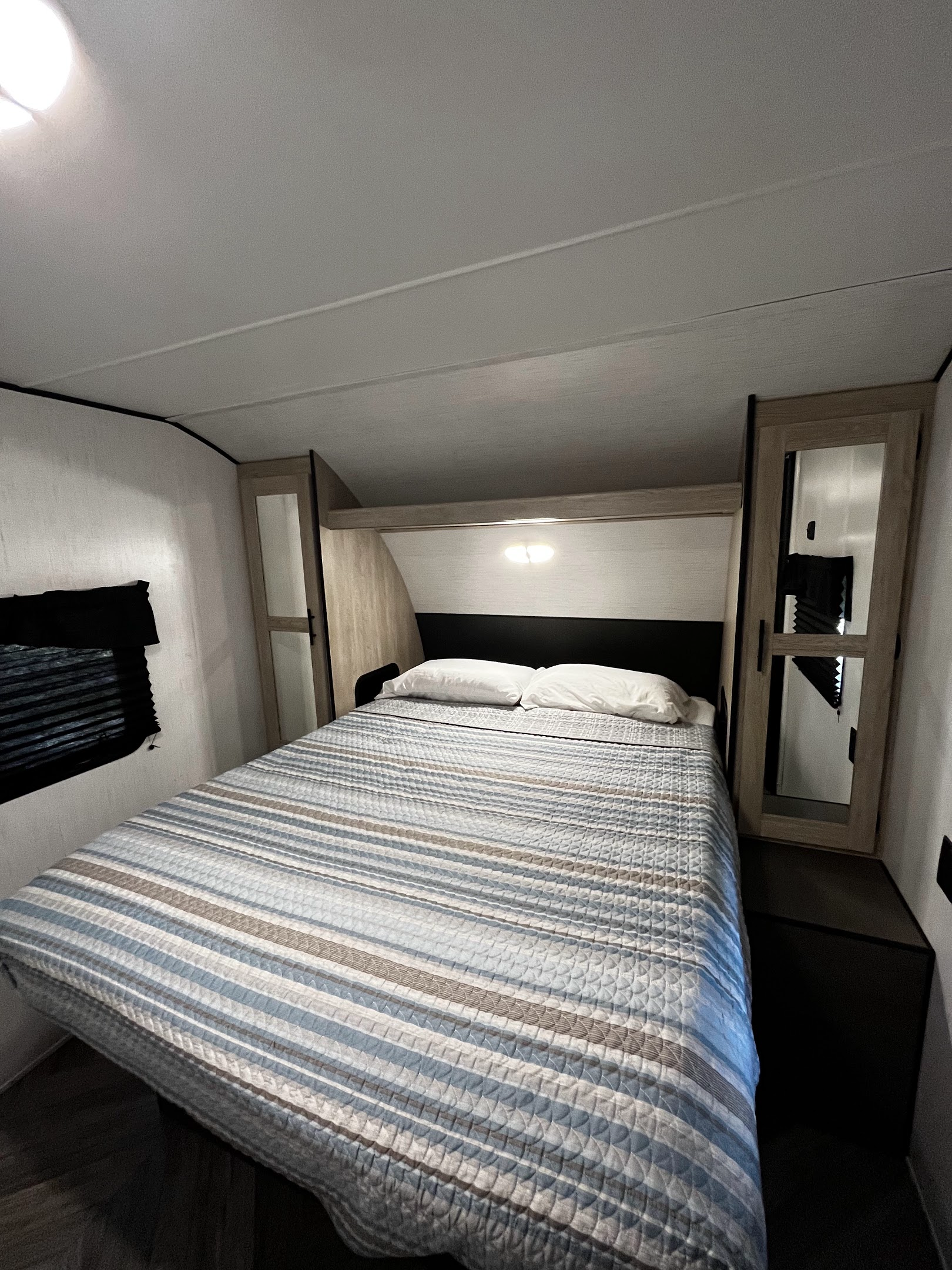 Modern RV rental bedroom with a comfortable queen bed, built-in storage, and bright overhead lighting.. Heartland Prowler 2022
