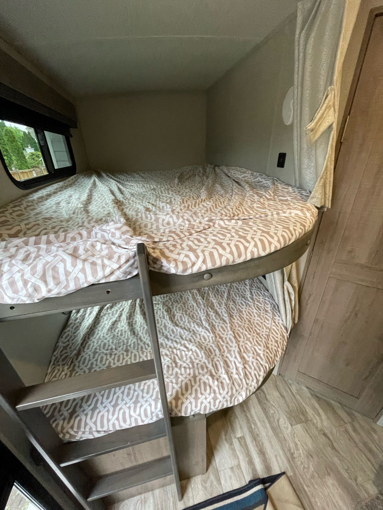 Two neatly made bunk beds with patterned sheets and a ladder visible, part of an RV rental interior.. Grand Design Imagine 2020