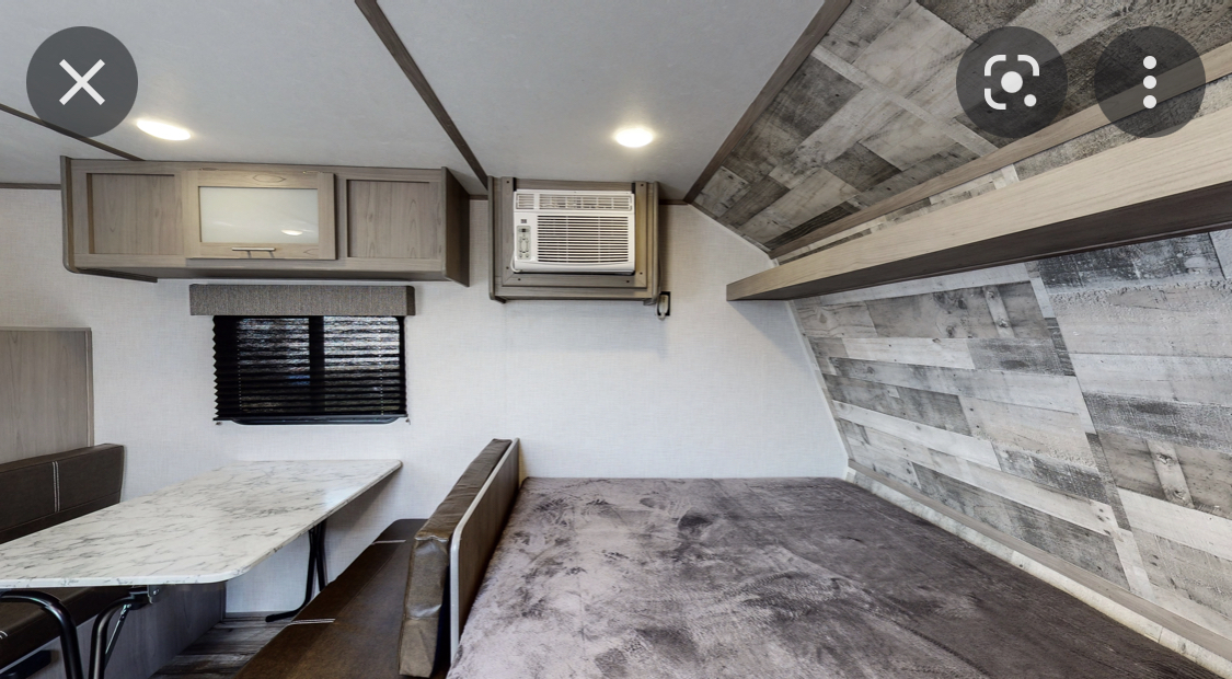 Compact RV rental interior: dining booth, bed, overhead storage, & AC unit. A functional and cozy living space.. Coleman Lantern 17b 2022