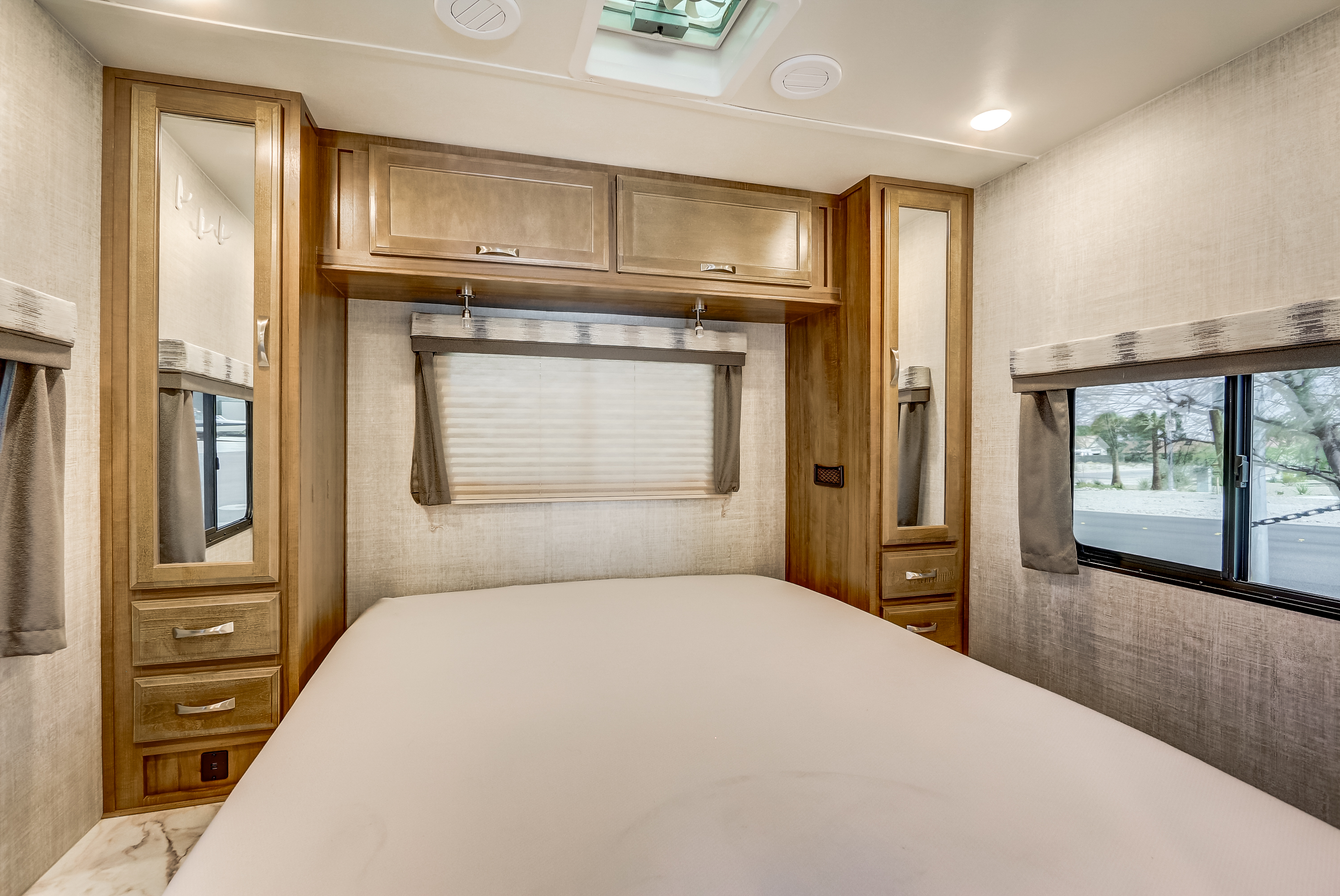 Inside a modern RV rental bedroom featuring a bed, ample wood cabinetry, mirrors, and large windows for comfortable travel.. Gulf Stream Conquest 2020