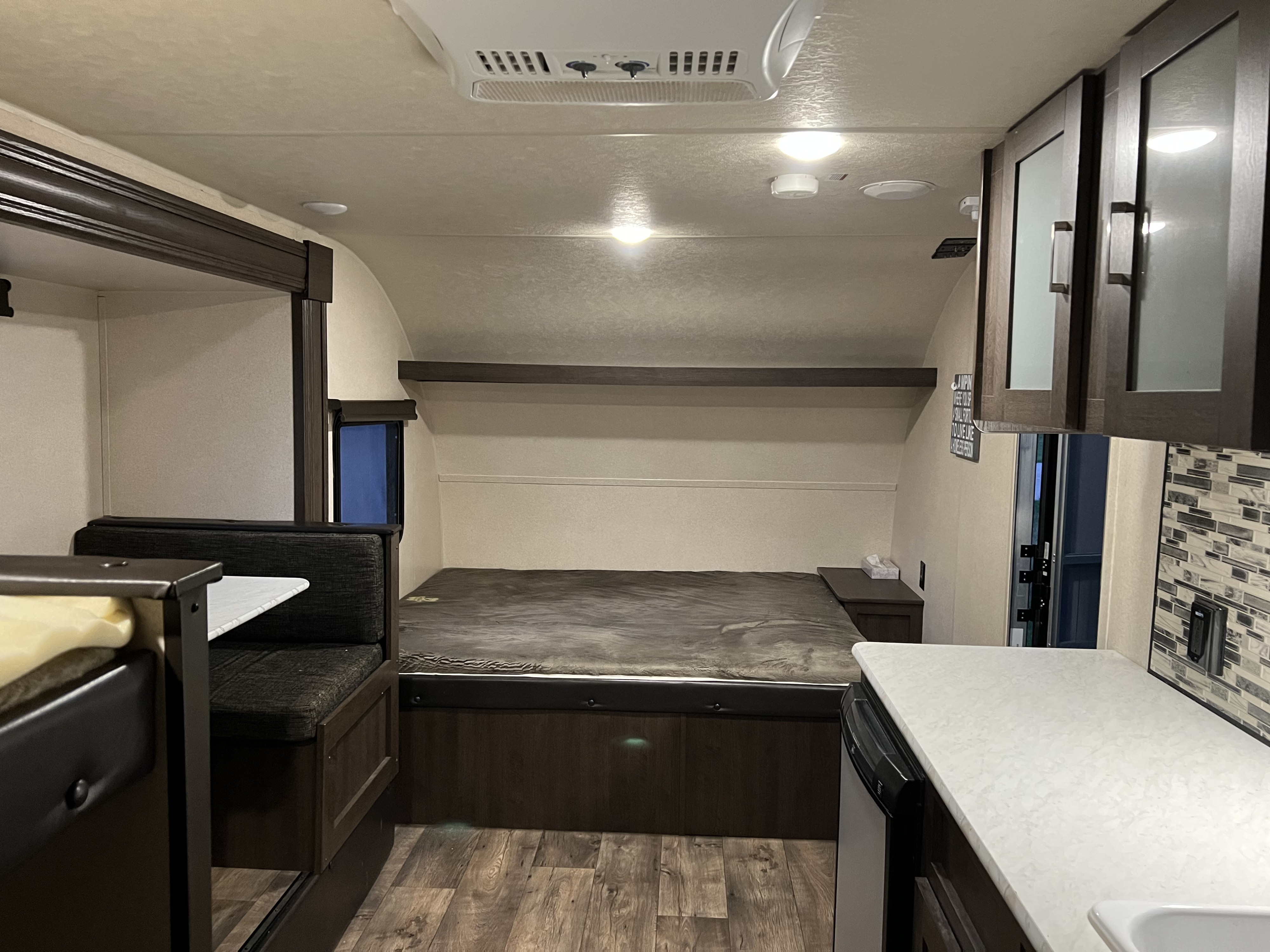 Interior of an RV rental showcasing a bed, dinette, kitchen with counters, and overhead AC unit. Ideal for camping trips.. Forest River Salem FSX 2018