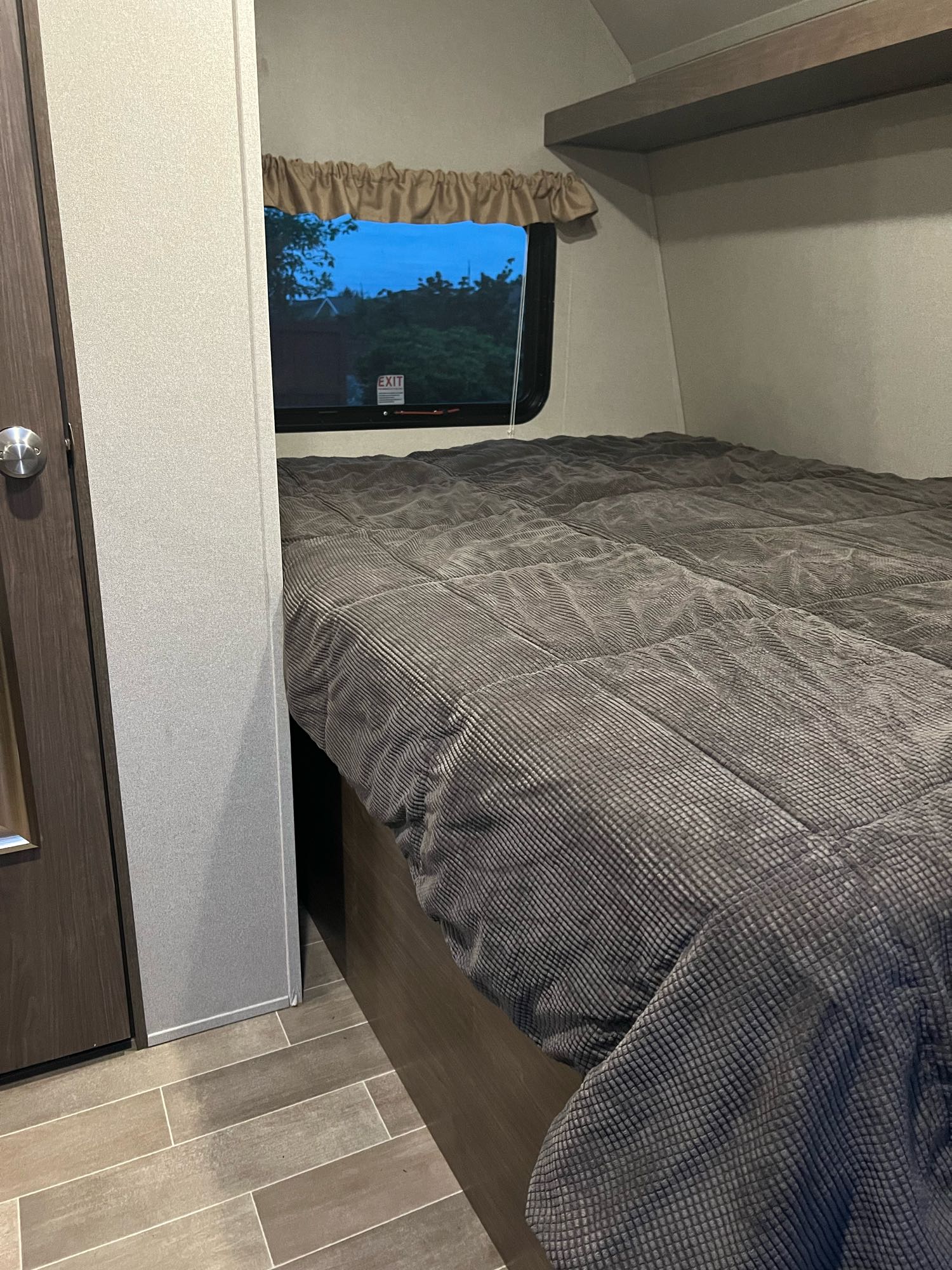Bedroom in an RV rental with a comfy bed, window, and wooden floor, ideal for restful travel.. Keystone RV Hideout LHS Mini 2019
