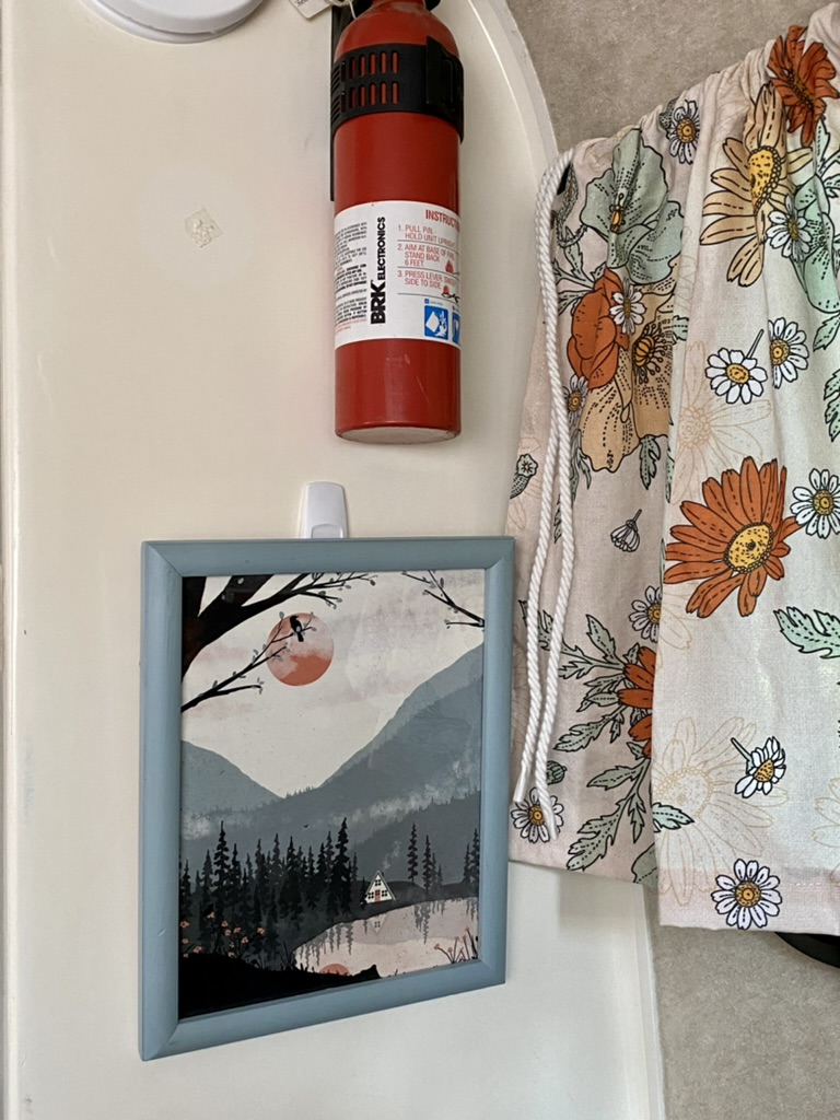 RV rental interior featuring a fire extinguisher, framed art, and floral fabric for safety and cozy decor.. Scamp Scamp Trailer 2000