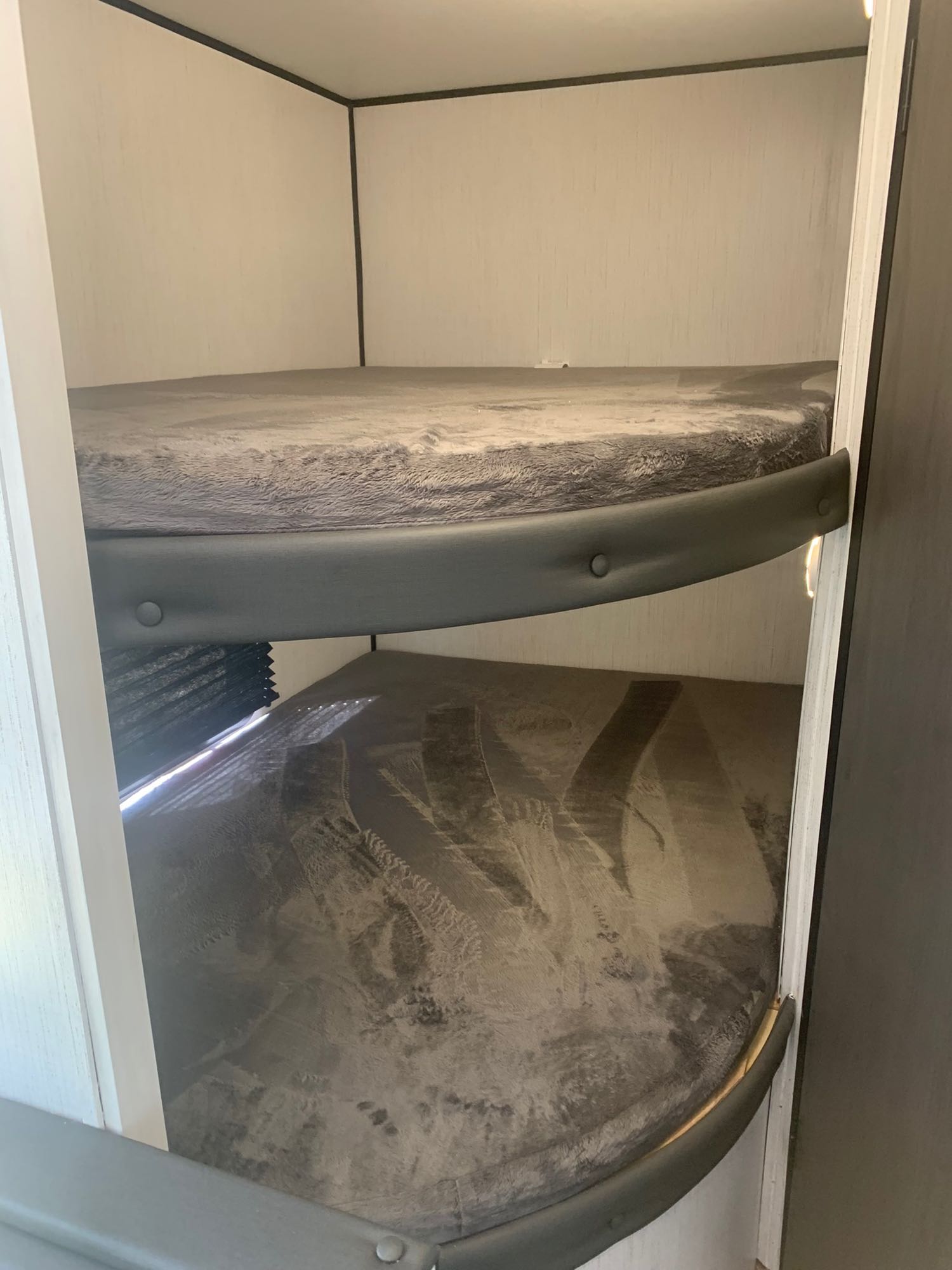 Inside an RV rental, two compact bunk beds with grey mattresses and safety rails provide cozy sleeping.. Heartland RVs Trail Runner 2022