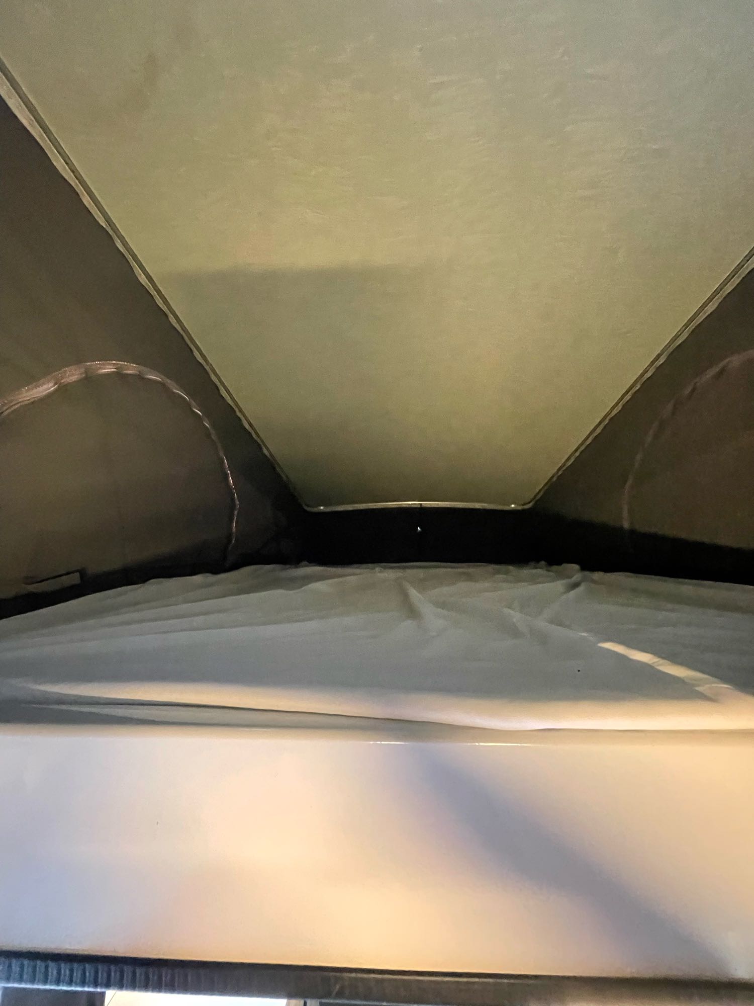 Interior of an RV rental pop-top camper, showing the elevated bed and fabric tent roof.. Winnebago Solis 2022