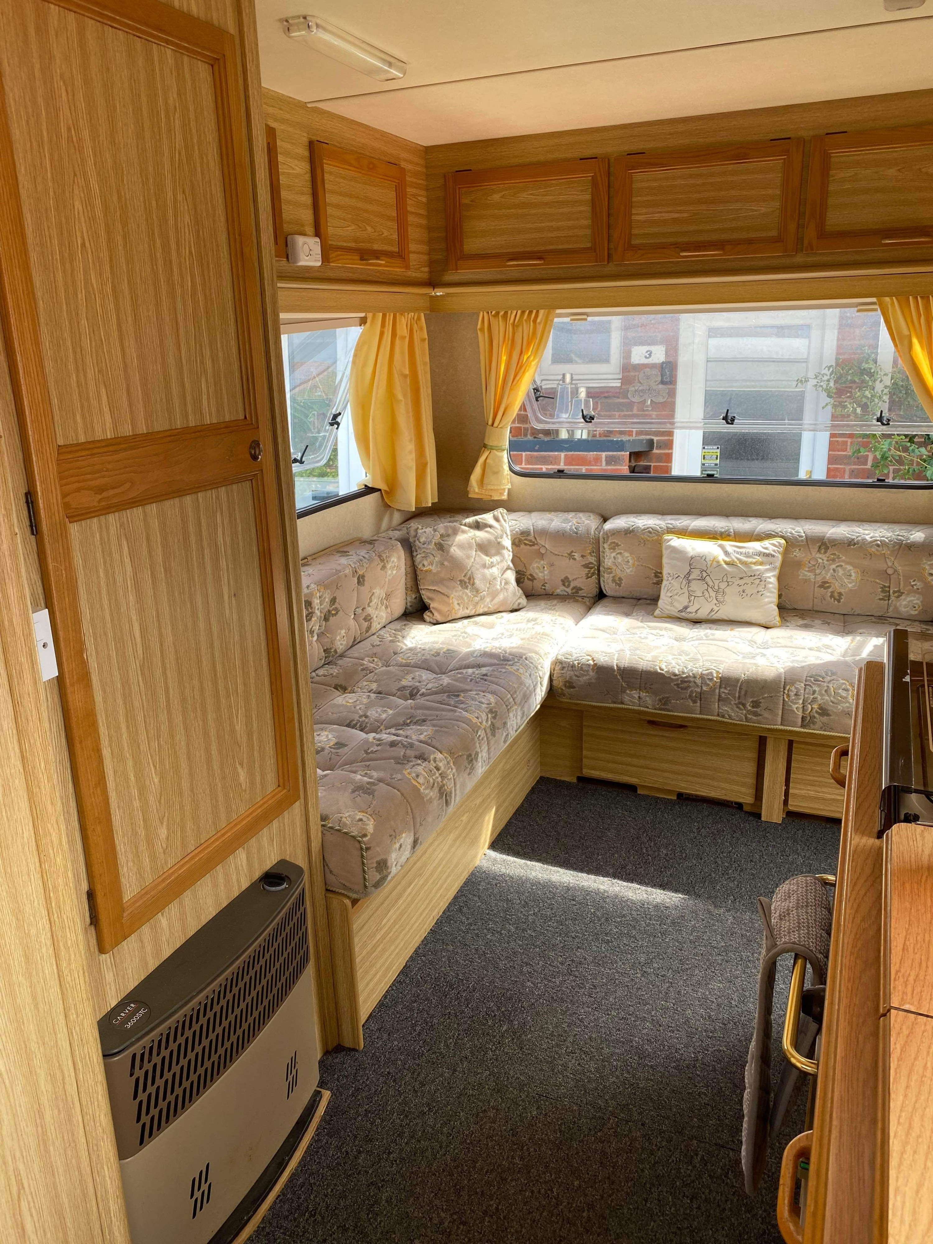 Relaxing RV rental interior with patterned corner seating, light wood cabinetry, a heater, and sunlit windows.. Peugeot Boxer 270 MWB 1998