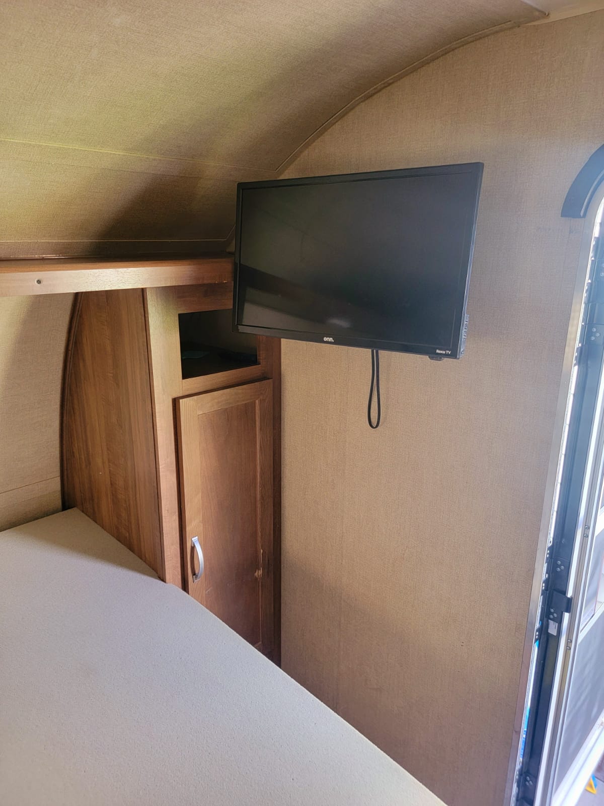 Interior of an RV rental with a flat-screen TV, wood cabinets, and bed. Ideal for comfortable travel.. Gulf Stream Ameri-Lite Super Lite 2019