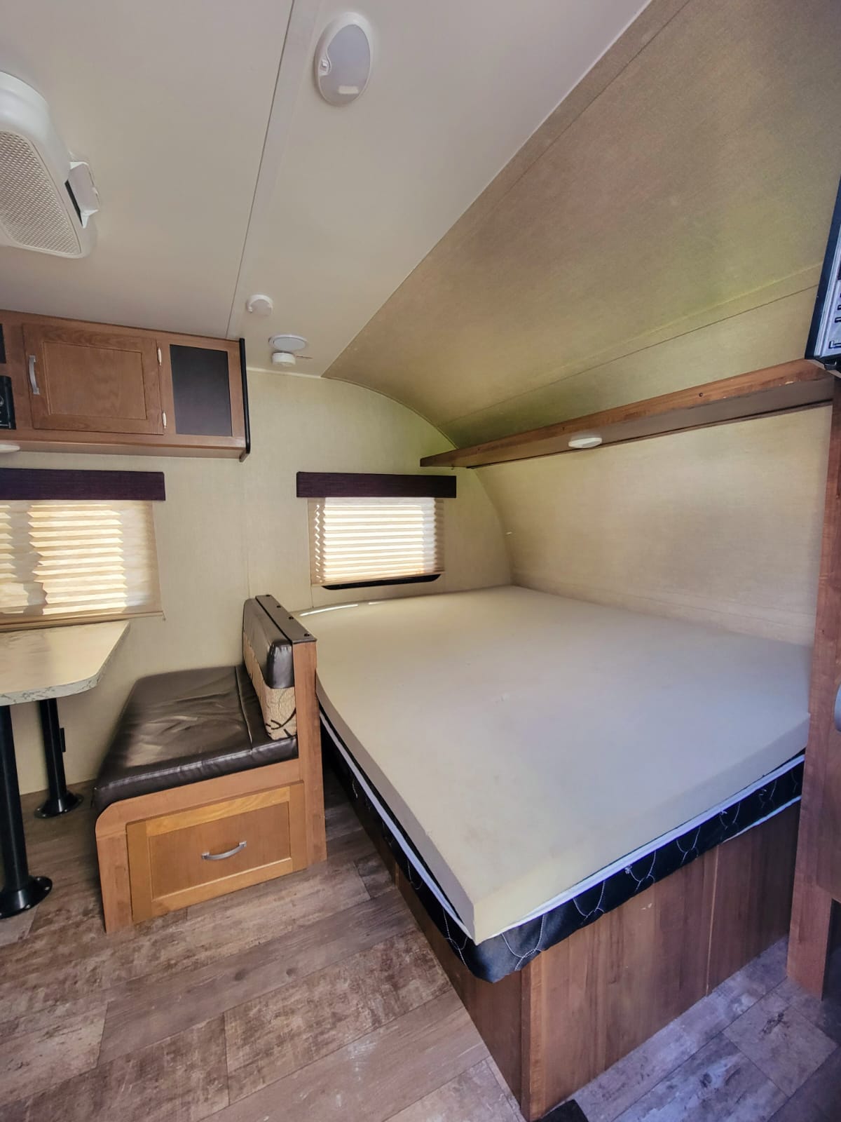 Inside an RV rental: a comfortable bed, small dinette, and wood cabinets, ready for your road trip.. Gulf Stream Ameri-Lite Super Lite 2019