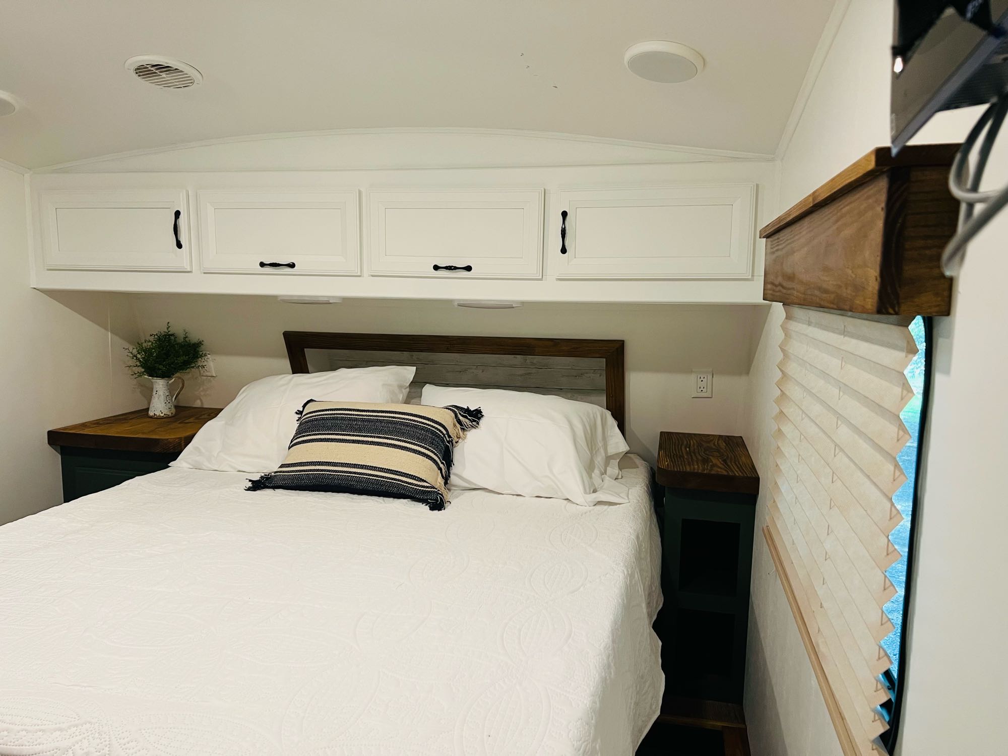 Inviting RV rental bedroom with a comfy bed, white quilted bedding, wood headboard, and storage cabinets.. Heartland RVs Greystone 2012
