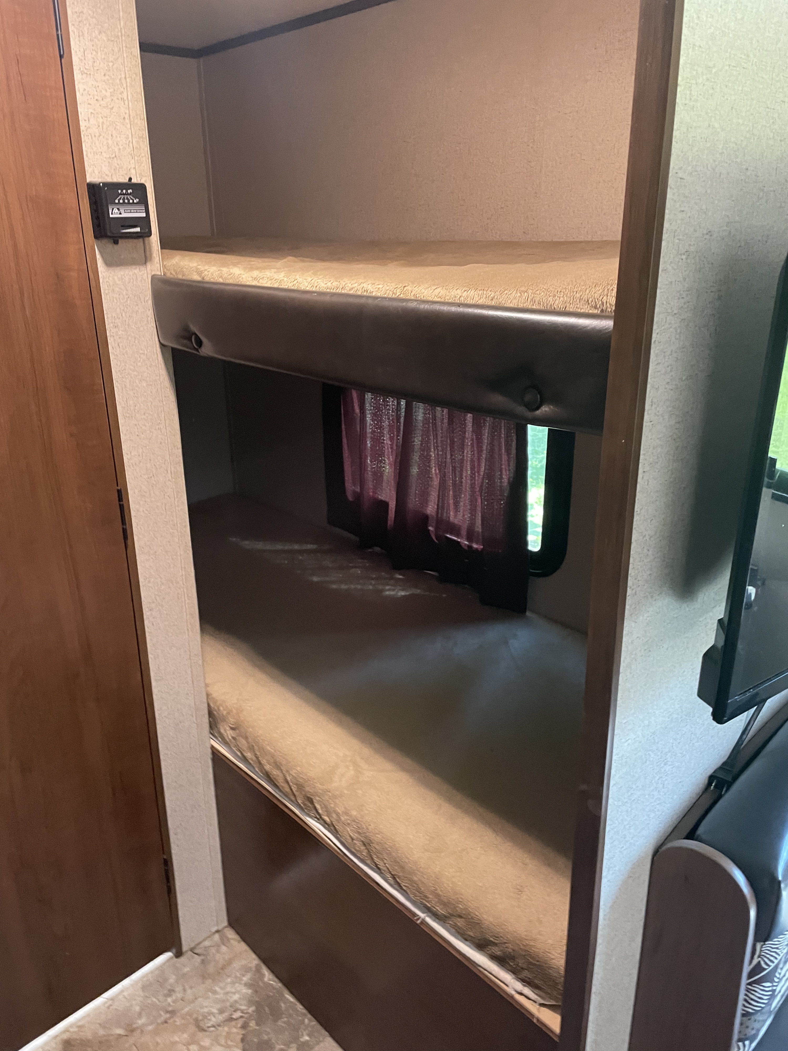 Inside an RV rental: a cozy sleeping area with two bunk beds, a window with curtains, and a control panel for comfort.. Jayco Jay Flight SLX 2016
