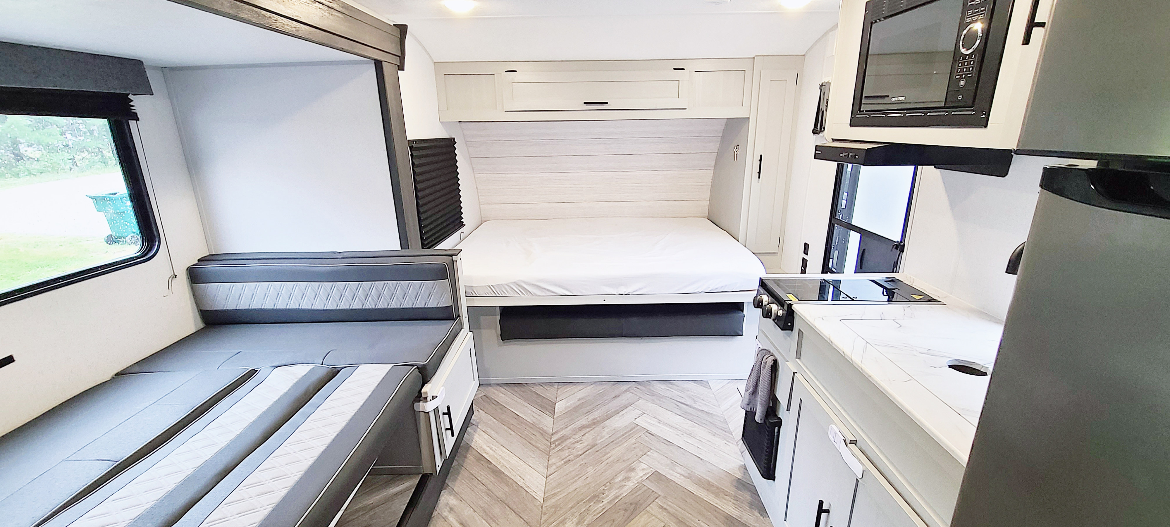 Modern RV rental interior showcasing a cozy bed, compact kitchen, and versatile dinette seating, ideal for comfortable travels.. Forest River Salem FSX Platinum 2022