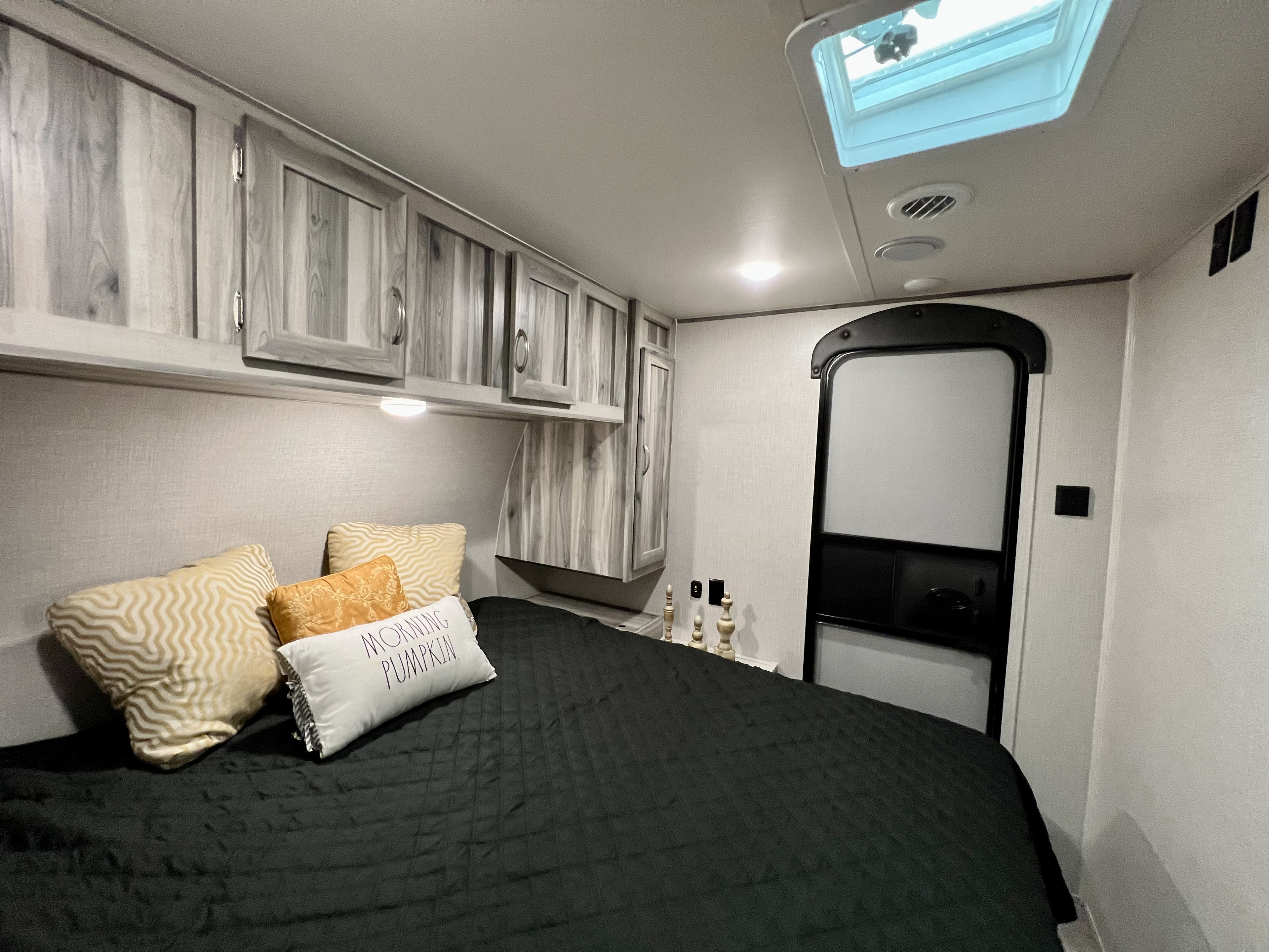 Cozy RV rental bedroom with wood cabinets, skylight, and comfy bed, perfect for your next adventure.. Dream 290DBS 2022