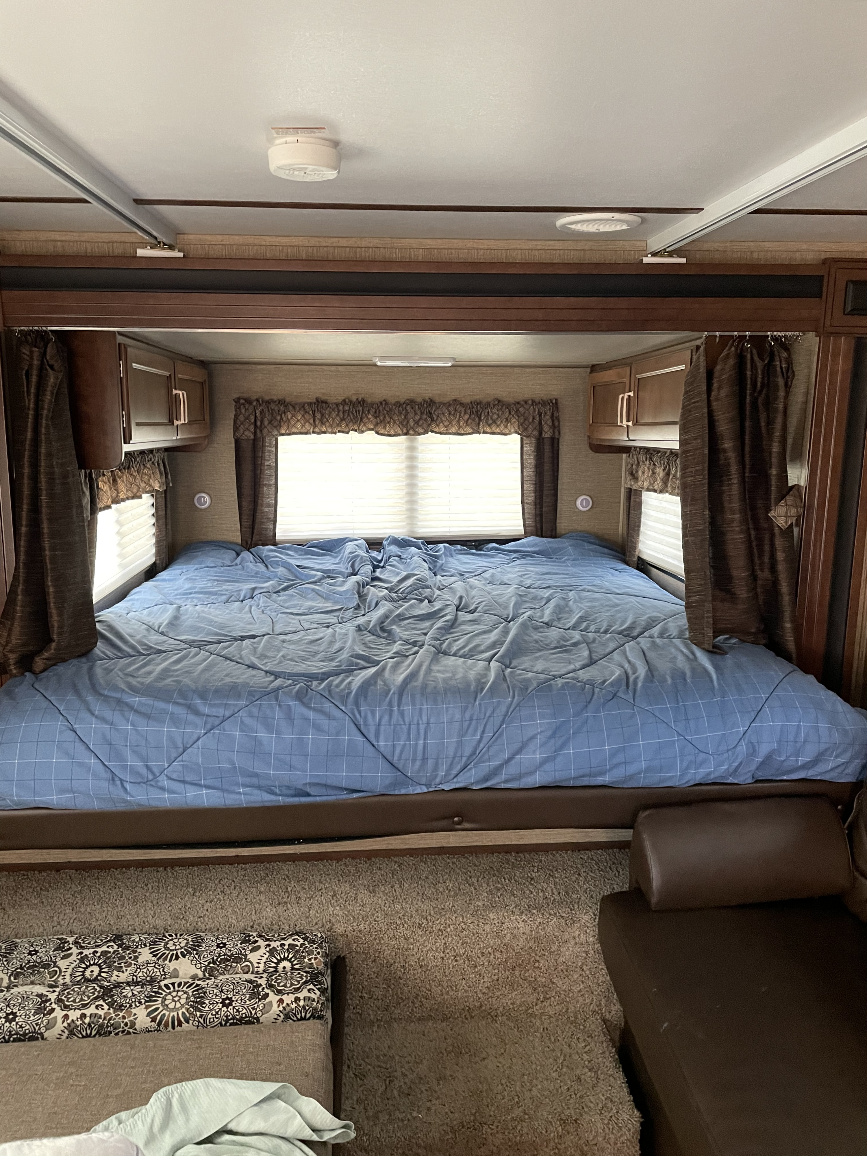 Cozy RV bedroom interior for your next rv rental adventure, featuring a comfy bed, windows, and storage.. Keystone Outback 2018