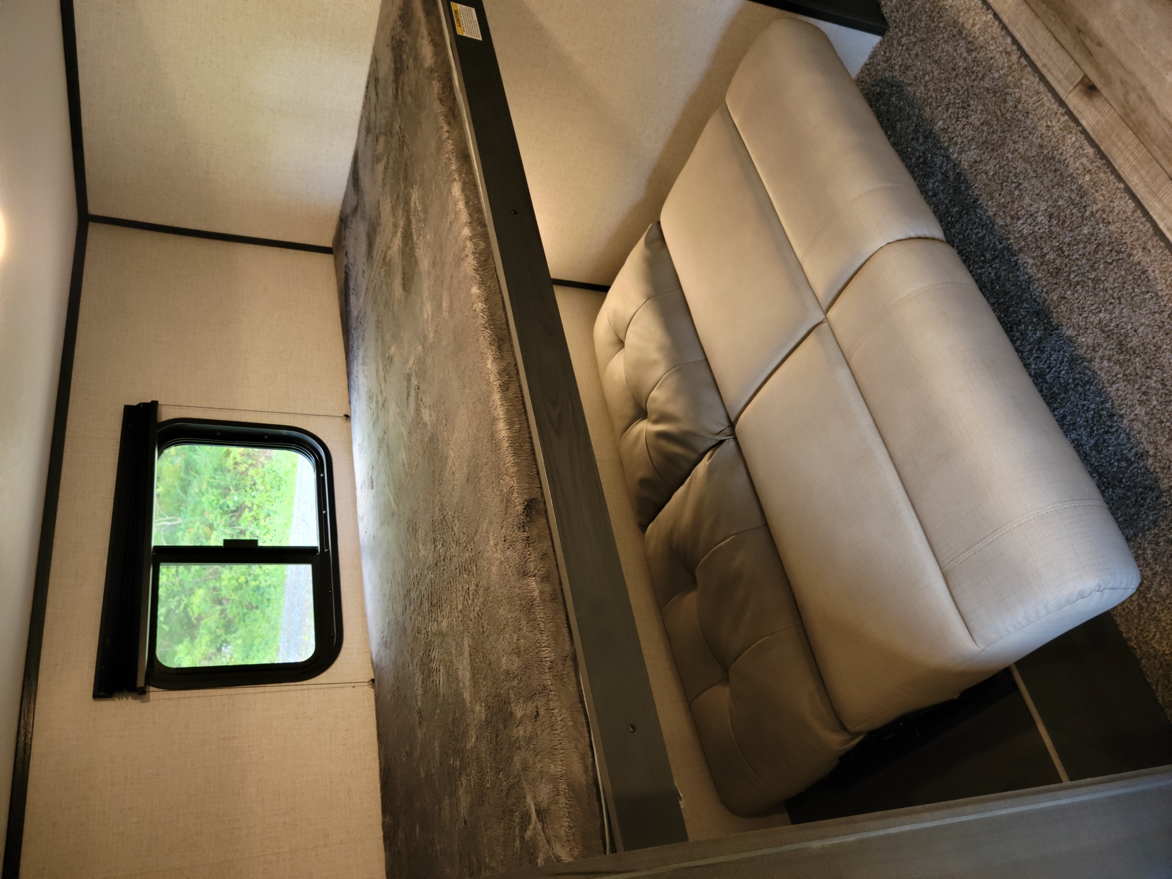 RV rental interior showing a compact bed, window, and comfortable upholstered seating.. Dutchmen Aspen Trail 2021