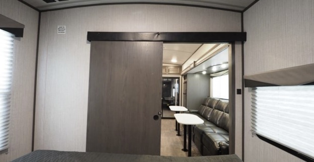 Inside this RV rental, a barn door opens to a comfortable living space with a sofa and dining tables.. Cruiser Rv Corp Stryker 2020