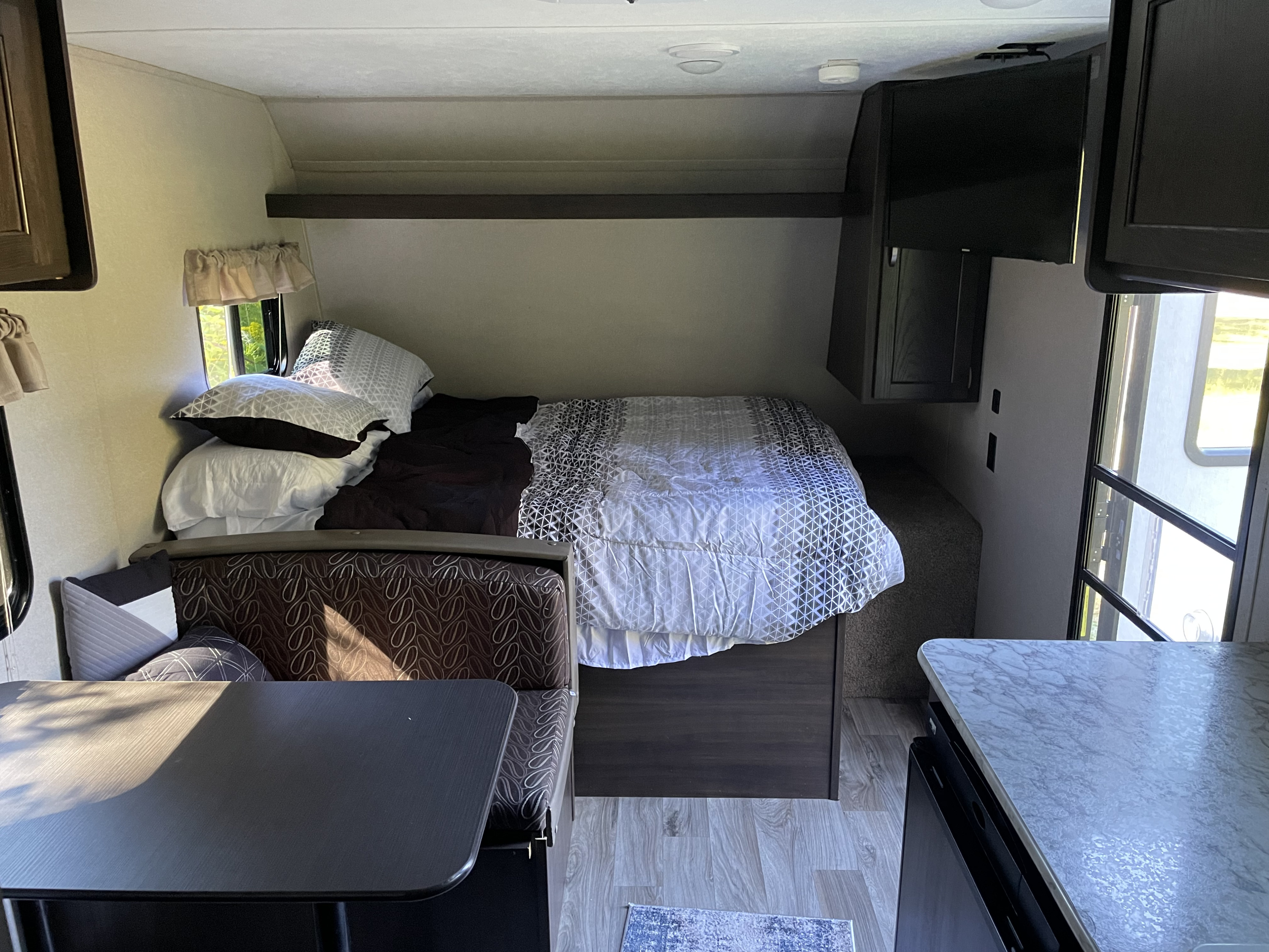 Cozy RV rental interior featuring a comfortable bed, dinette area, and kitchen counter for your next adventure.. Keystone RV Springdale Mini 2019