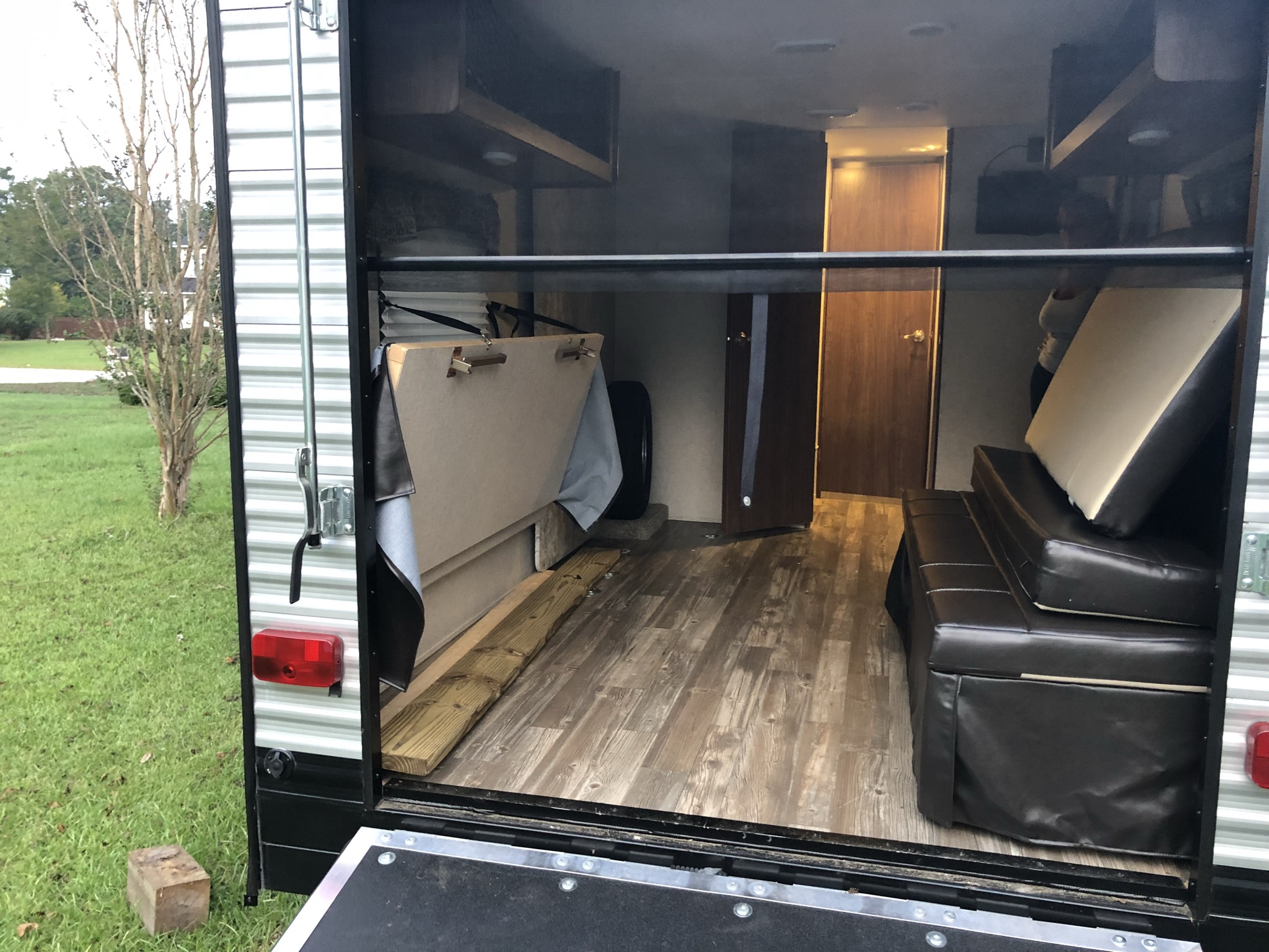 RV rental: An open toy hauler's interior reveals modular seating, wood-look flooring, and a folded bunk, viewed from the rear ramp.. Heartland RVs Pioneer Toy Hauler 2017