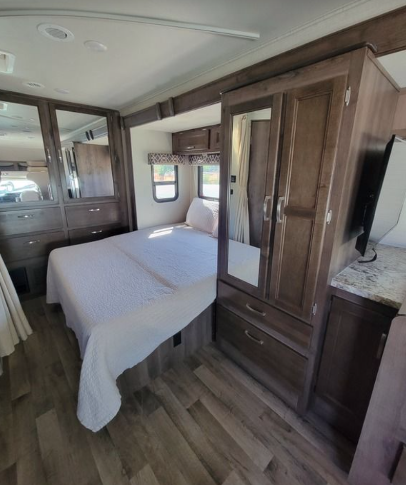 Experience comfort in this RV rental bedroom featuring a full bed, mirrored wardrobes, and storage. Ideal for travel.. Jayco Redhawk 2020