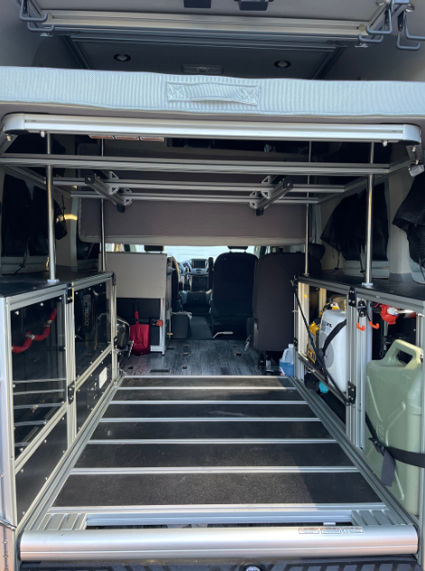 Inside an RV rental: a versatile cargo space with a modular aluminum bed frame and side storage.. Ford T350 XLT 2019