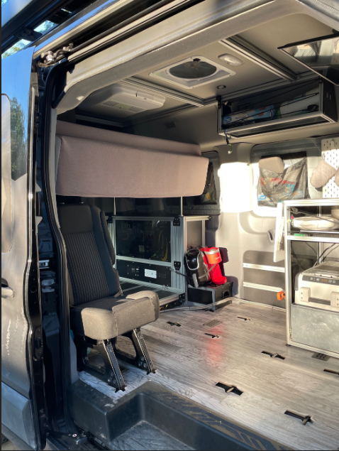 Spacious RV rental interior: modular seat, fold-down bed, and custom storage setup inside this versatile camper van.. Ford T350 XLT 2019