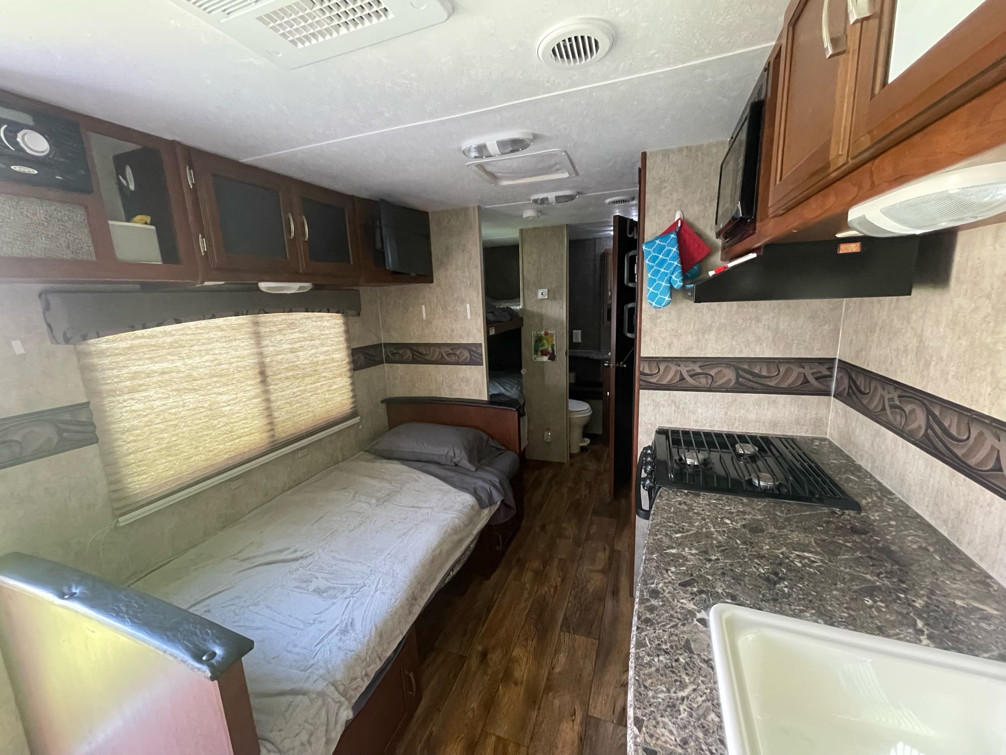 Spacious RV rental interior with bedroom, kitchen, and bathroom view, plus bunks. Perfect for travel.. Keystone RV Passport Ultra Lite 2015