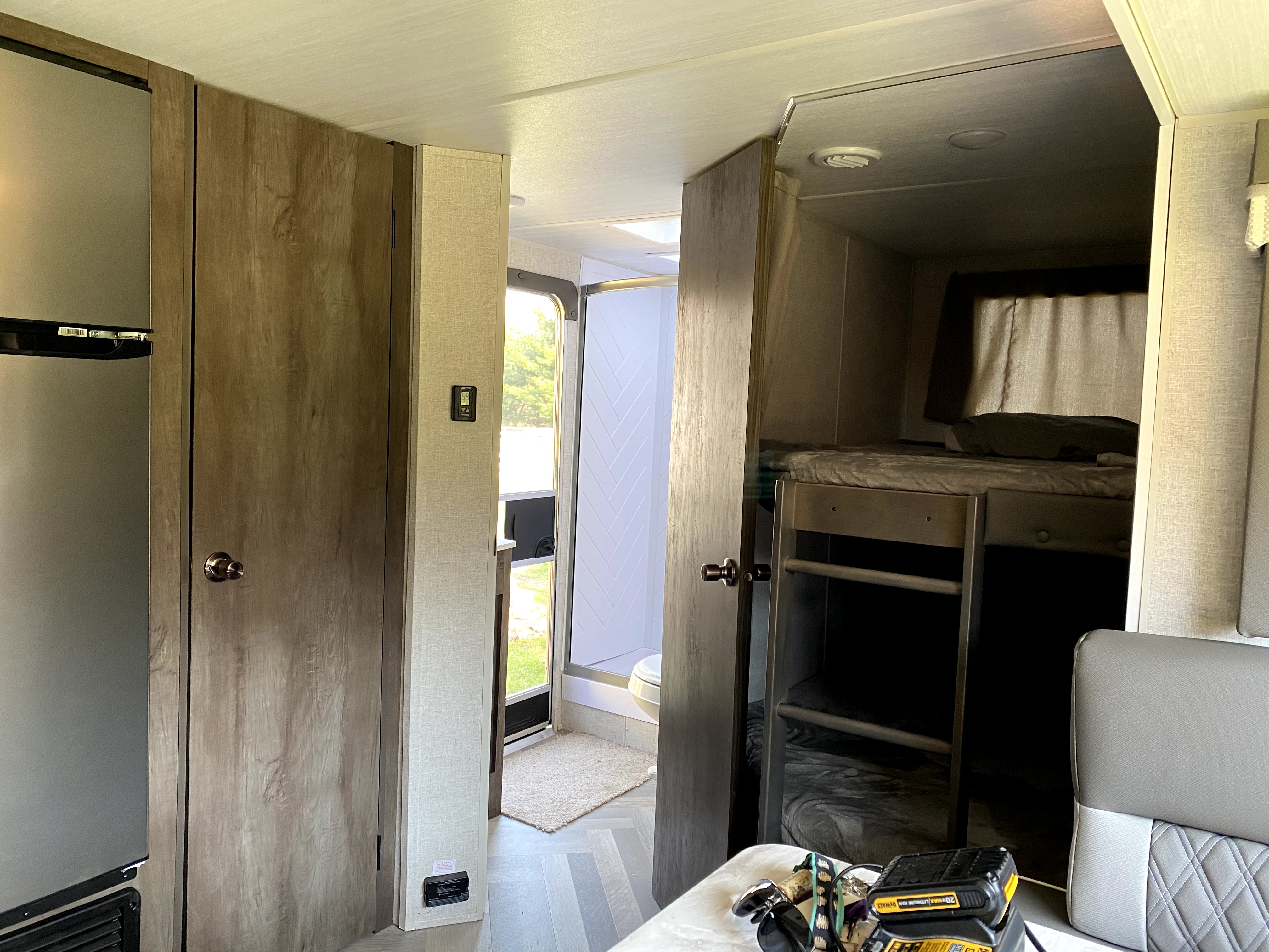 RV rental interior: fridge, pantry, hallway leading to bathroom, and bunk beds. Compact living space with modern finishes.. Forest River Wildwood X-Lite 2021