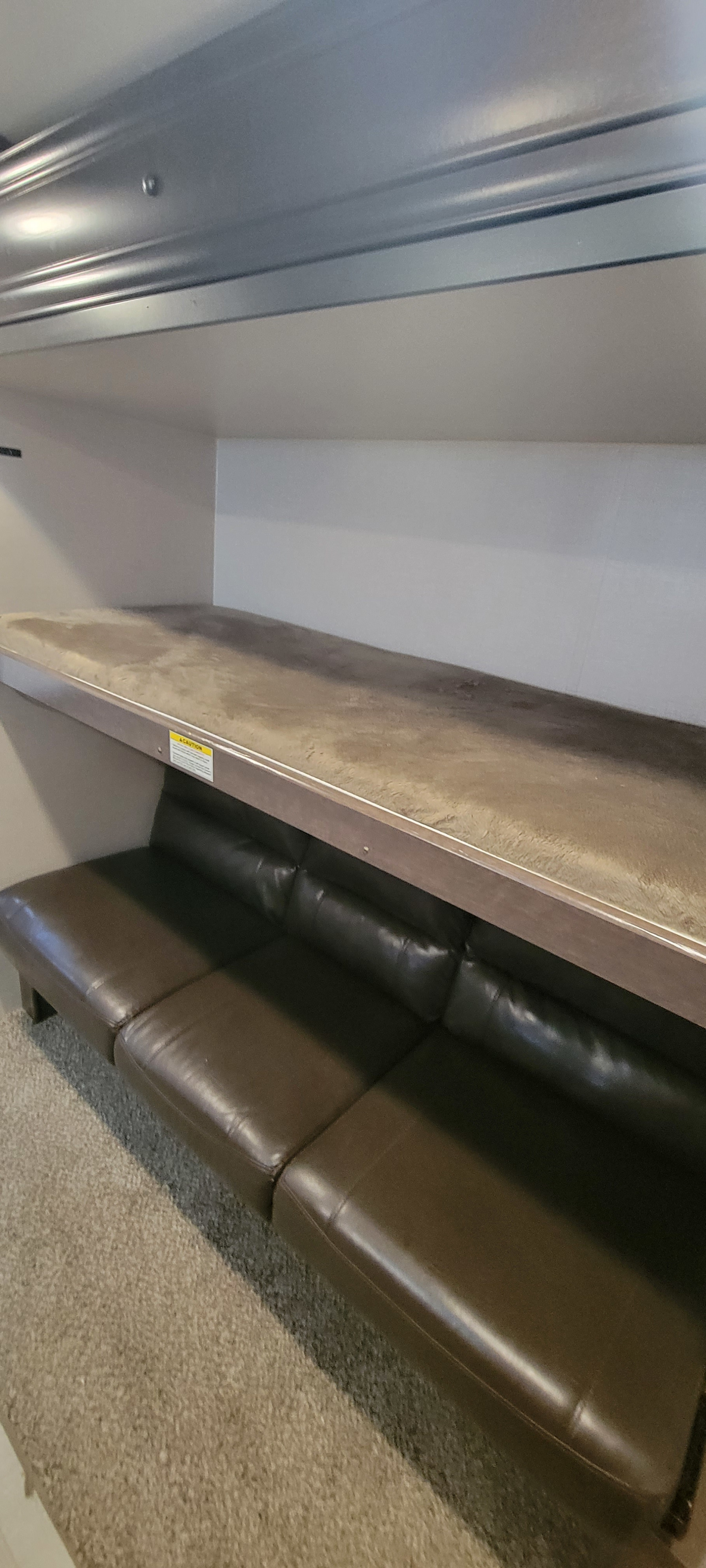 This **RV rental** features a cozy bunk bed over a brown leather sofa, with carpeted floor. Ideal for compact living spaces.. Crossroads RV Sunset Trail Super Lite 2019