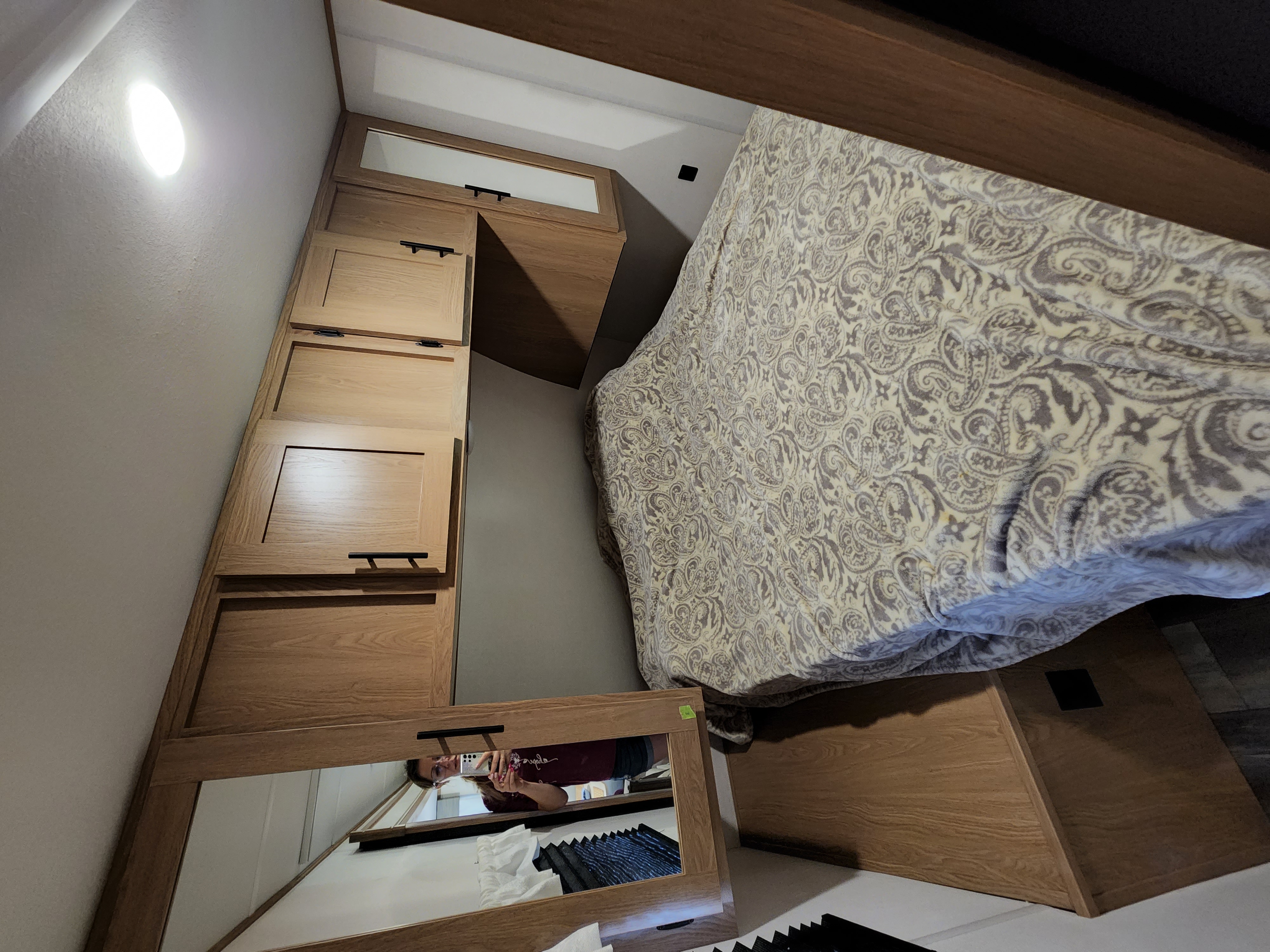 Discover this cozy RV rental bedroom: light wood cabinets, a comfy bed with a paisley comforter, and a mirror.. Avenger Avenger Trailer 2022